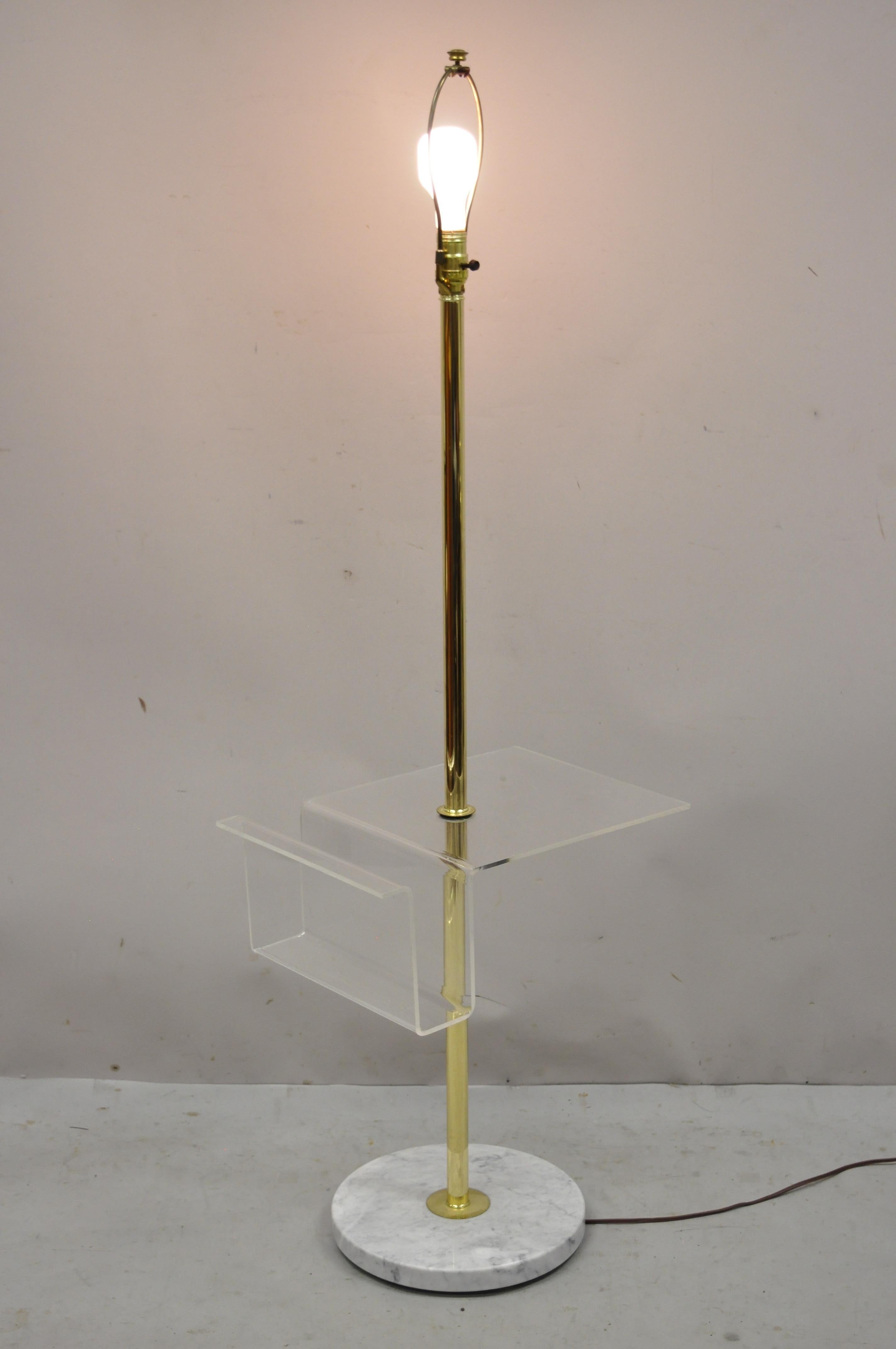 Italian Mid-Century Modern brass pole floor lamp with marble base and lucite magazine rack. Item features clear lucite magazine rack table surface, brass shaft, round white marble base, very nice vintage item, clean modernist lines, great style and