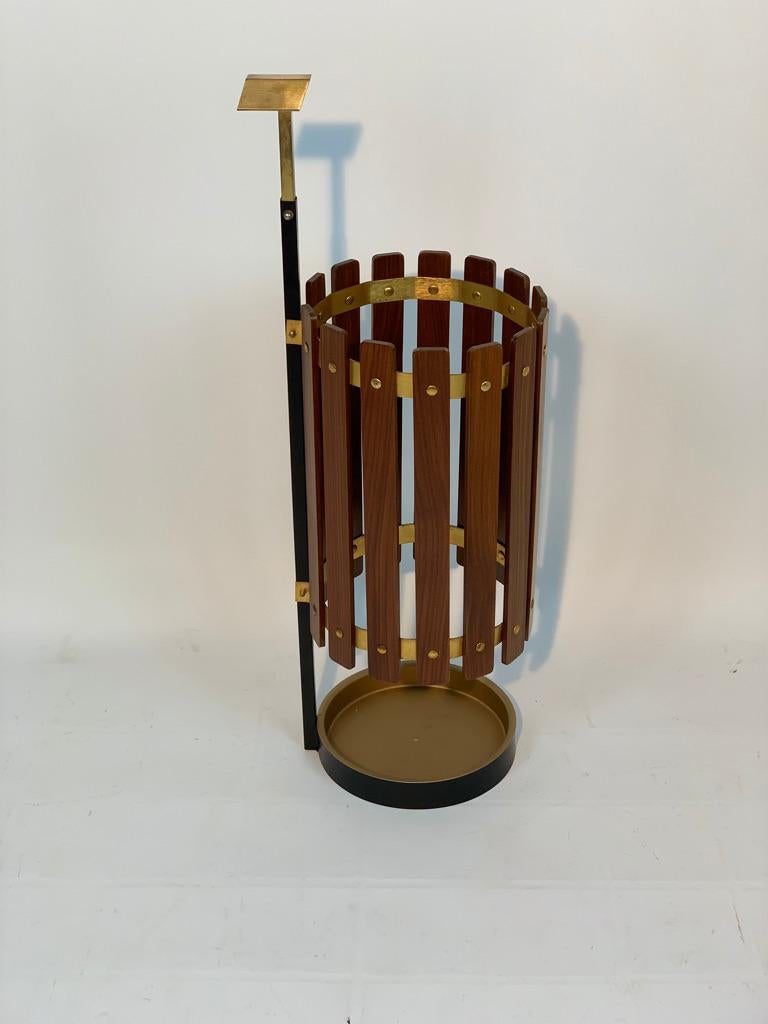 Italian umbrella stand late 50's in brass and black lacquered brass and teak.
Through the practical handle it can be moved easily, the bottom tray can be extracted to empty any water deposited by the umbrellas.