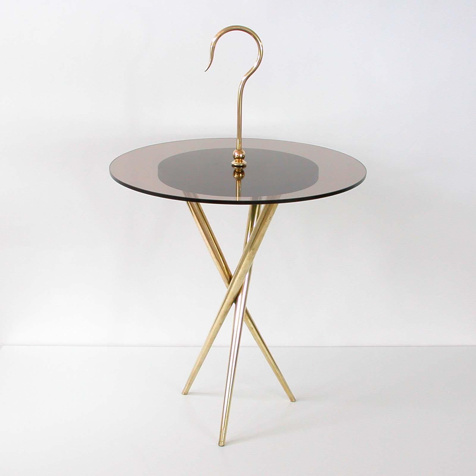 Cette table d'appoint ronde à trépied a été fabriquée en Italie dans les années 1950 à la manière d'Ico Parisi. Il a une base en laiton, un plateau en verre teinté bronze (fumé) et une poignée et des détails en laiton. La hauteur totale avec la
