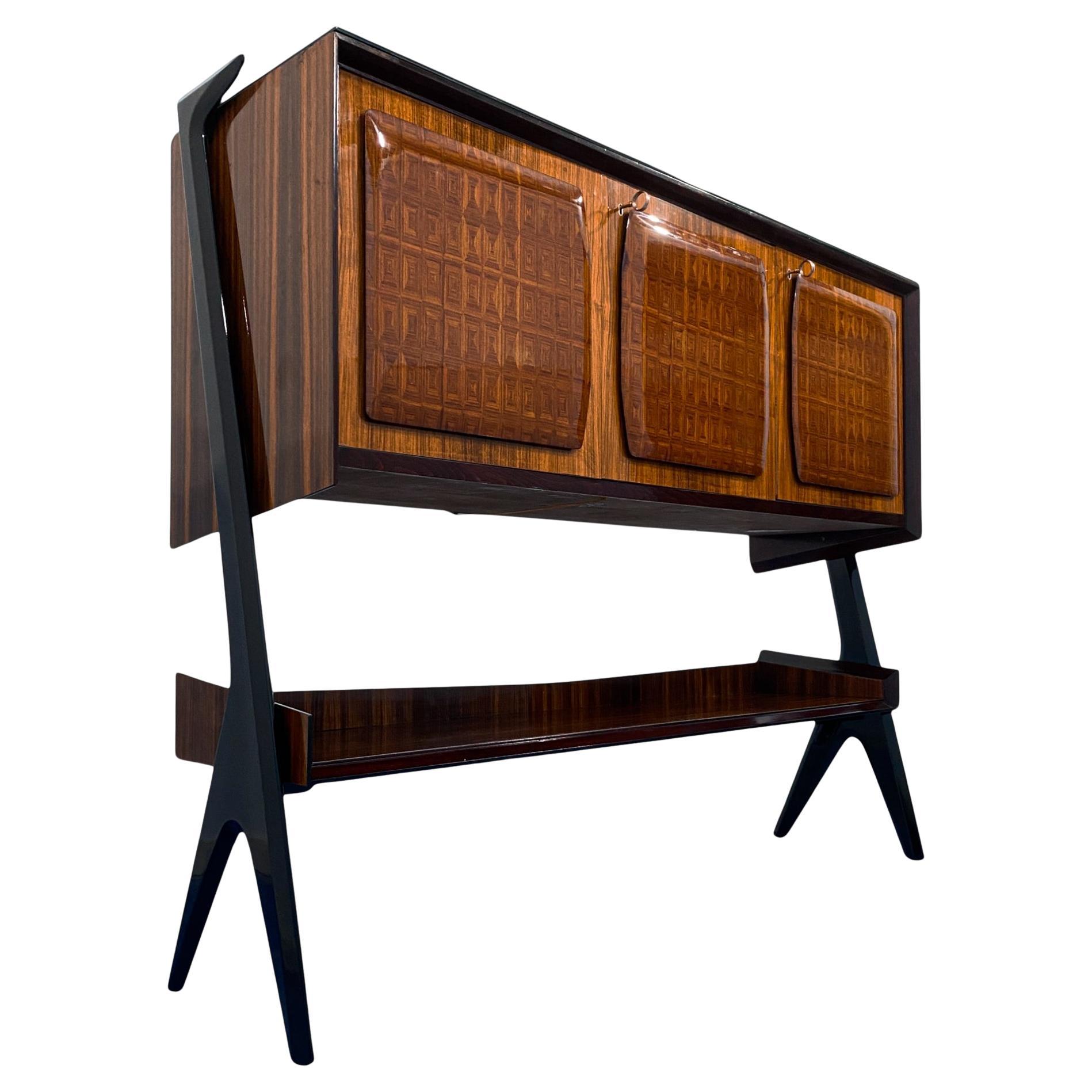 Si tratta di una credenza dallo stile unico, un mobile bar disegnato da Vittorio Dassi nel 1955 e realizzato con materiali di grande qualità. Da notare il design raffinato dei sostegni laterali in legno laccato nero, le tre ante con la parte