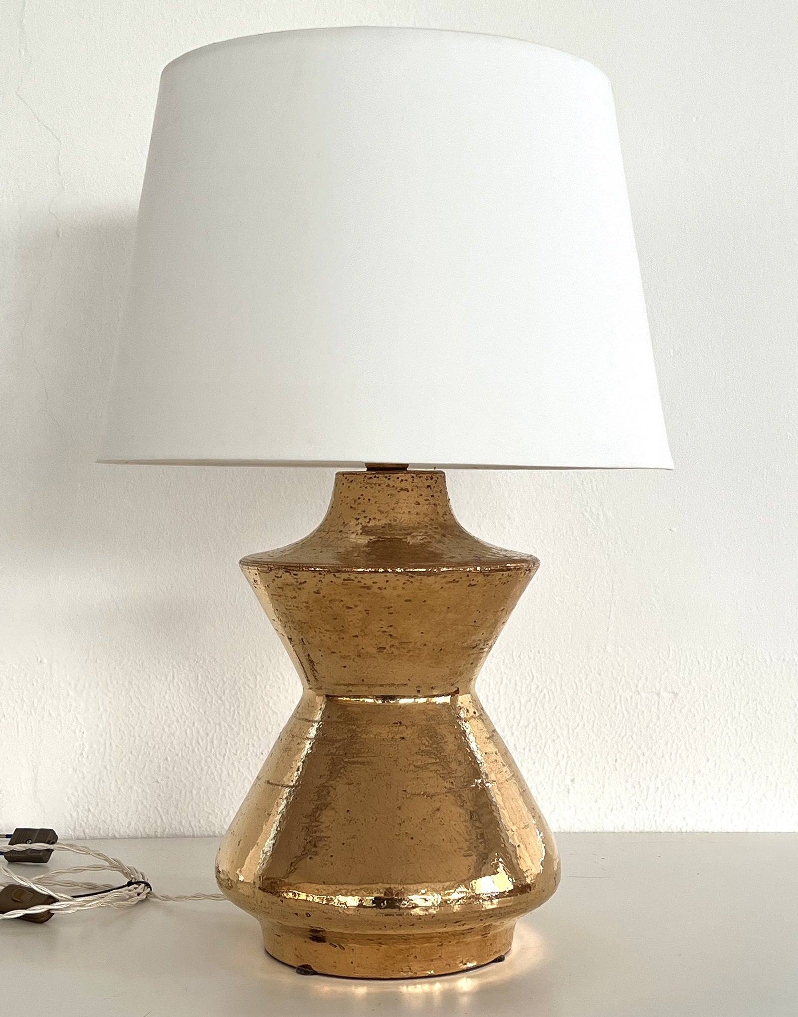 Wunderschöne glänzende Keramik-Tischlampe, entworfen und hergestellt von Aldo Londi in den 1970er Jahren für Bitossi.
Dieser schwere, organische Keramikkörper ist in goldener Metallic-Glasur gefertigt und ein schöner Blickfang.
Es ist in wunderbarem