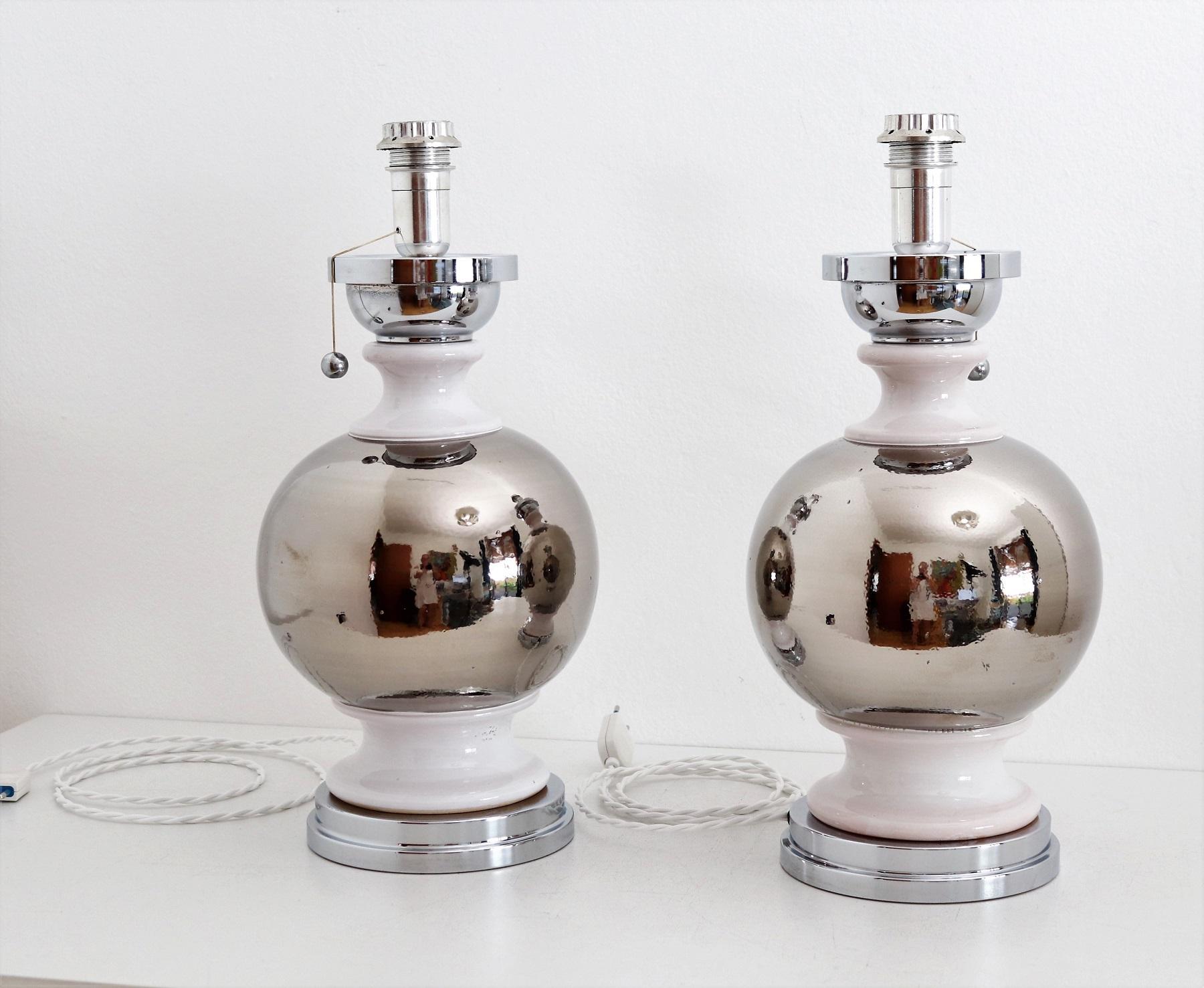 Gorgeous pair of big Italian table lamps made of strong ceramic parts and painted with platinum silver and white glaze.
They remind to the style of Aldo Londi for Bitossi.
The lamps are based on a metal part.
The are switched on/off with a cord and