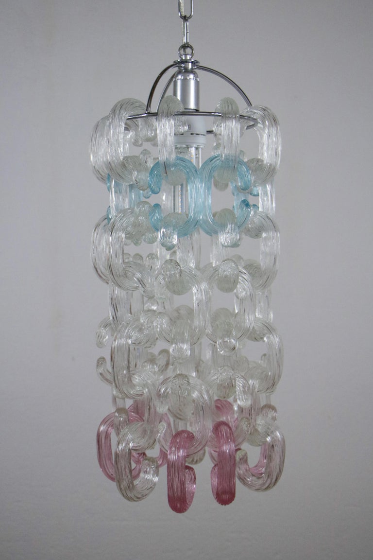 Toso brothers created this unique Italian midcentury chandelier in the 1970s. It is made of chromed brass and Murano chain glass. Pink and turquoise are featured in some pieces. The pieces of the chandelier are interchangeable, so you can assemble