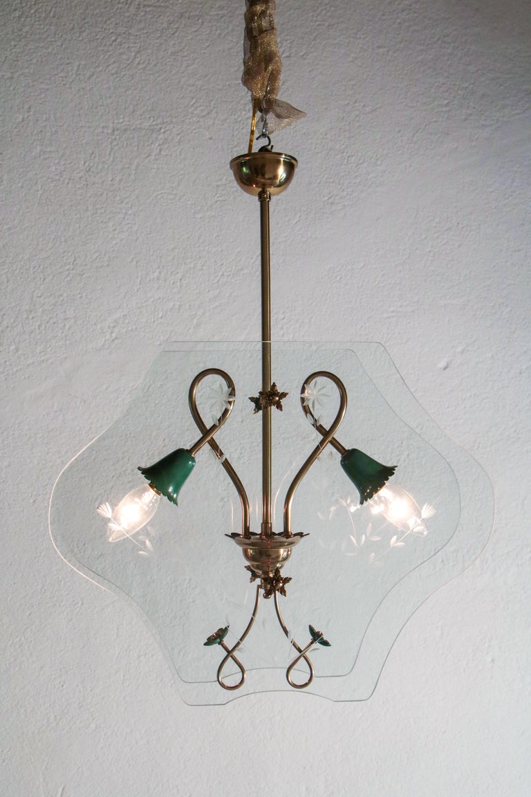 Elegant and stylish Italian mid-century chandelier in the style of Pietro Chiesa per Fontana Arte, from the 1940s.
Two lights, polished brass structure, green aluminum lamp holder, and floral print glasses. The restoration was made with great care