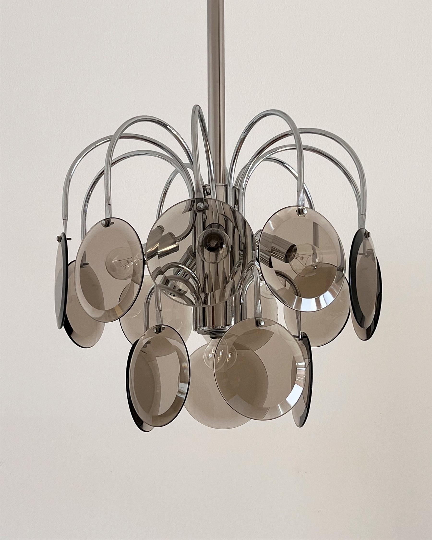 Stunning original chandelier back from the 1970s, Made in Italy.
Strong chrome base with some patina and vintage spots, holding 15 Murano glass discs with cut glass edges in smoked, light brown transparent color. Leave beautiful shadows.
The discs