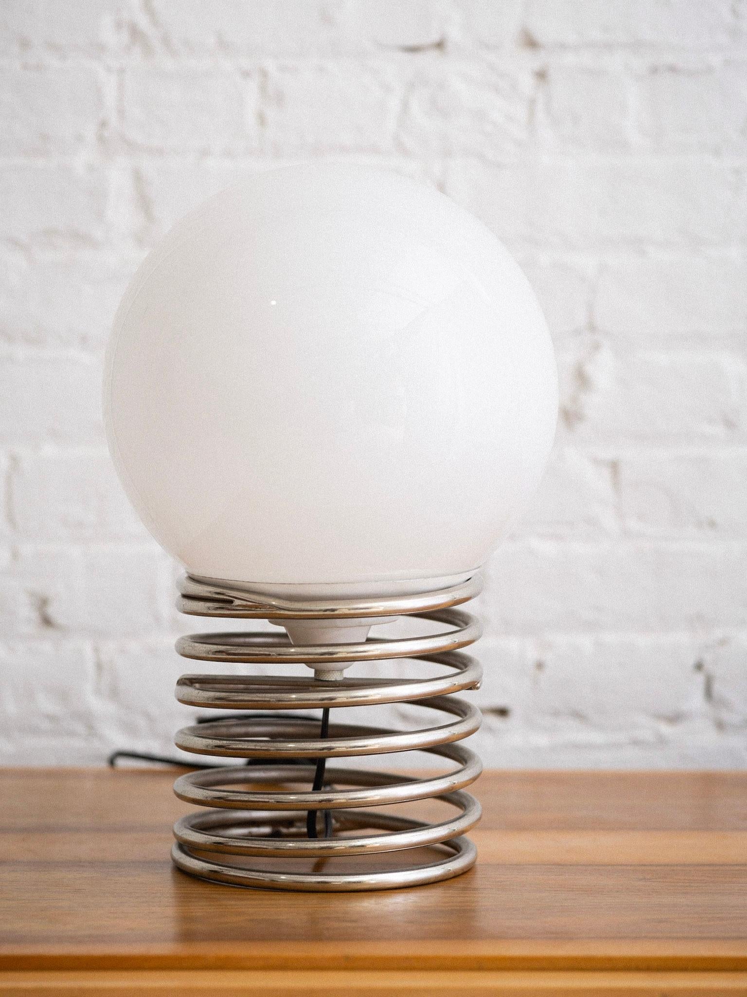 A midcentury Italian chrome and glass table lamp. Glass globes sits securely atop the chrome spring base. Sourced in Northern Italy. Two available, sold separately.
