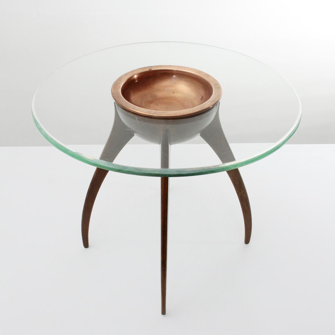 Italian manufacturing table produced in the 1940s.
Structure in shaped wood.
Circular glass top with a tapered edge.
Central copper cup, removable. 
Good general conditions, some signs due to normal use over time.

Dimensions: Diameter 42 cm,