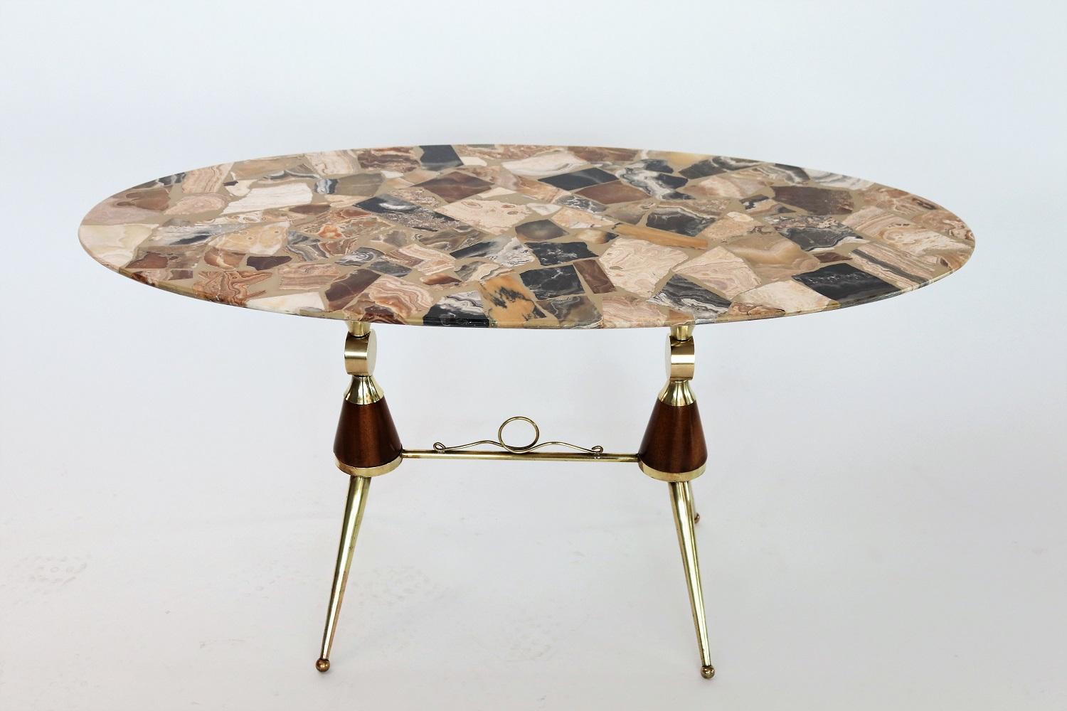 Gorgeous and particular coffee table composed of a table base with mahogany and full brass details and an oval marble tabletop.
The table top is made of marble pieces composed as a mosaic and resin.
Typical shape of Italian manufacturing of the