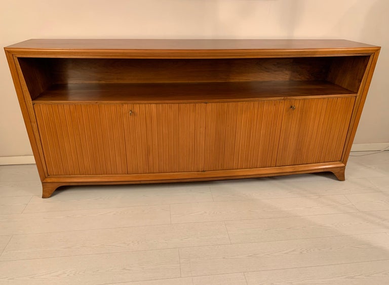 Convex sideboard Made in Florence Italy in the 1940s with a beautiful light walnut, four grooved doors and open compartment.
Inside the doors it has shelves and four drawers on the left side.
This buffet is more dept in the center cm 47 / inch