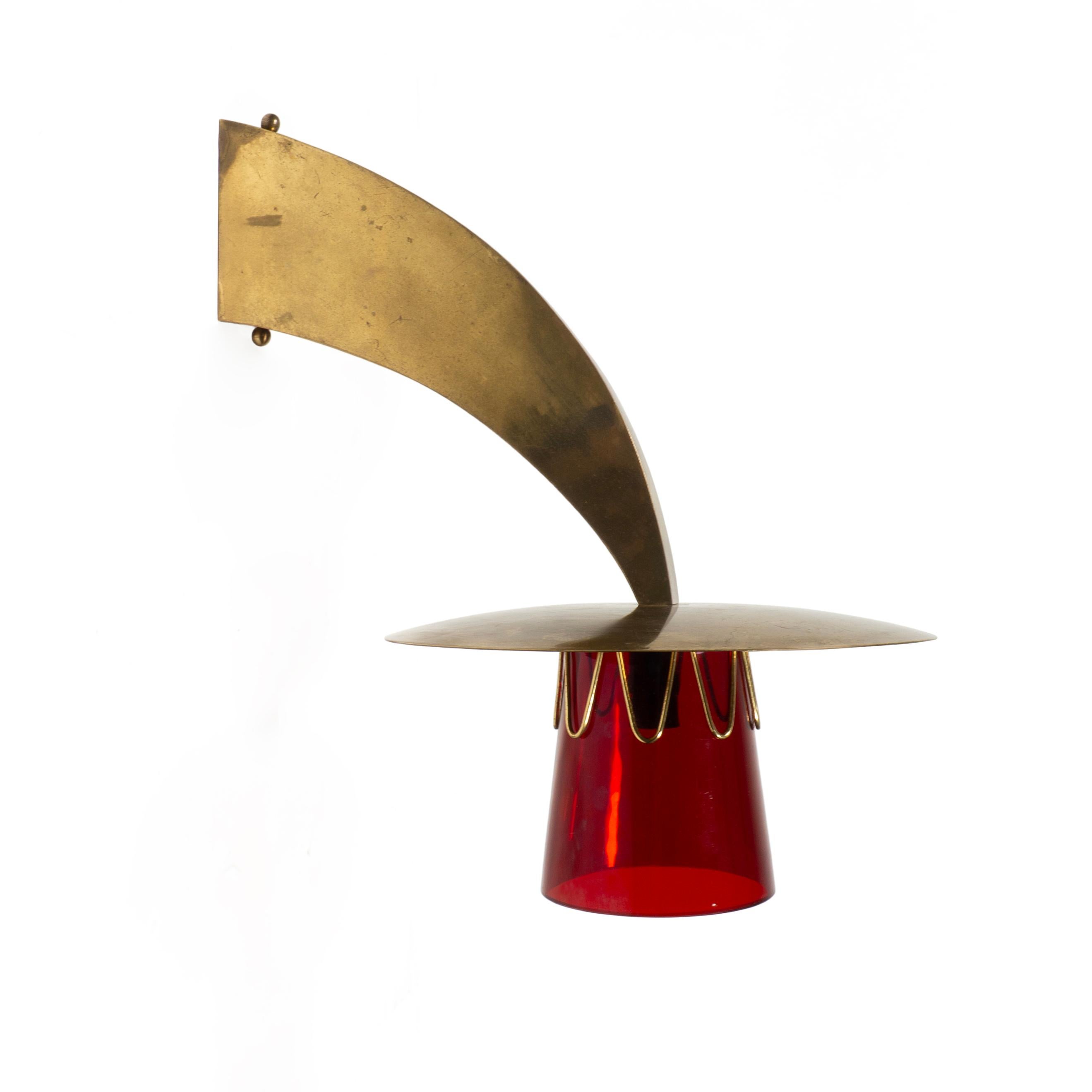Applique en laiton et en verre exceptionnellement rare et magnifiquement conçue, datant des années 1950. 
L'applique est en laiton et est complétée par un abat-jour en verre rouge épais maintenu par des boucles en laiton.
Avec son design intemporel
