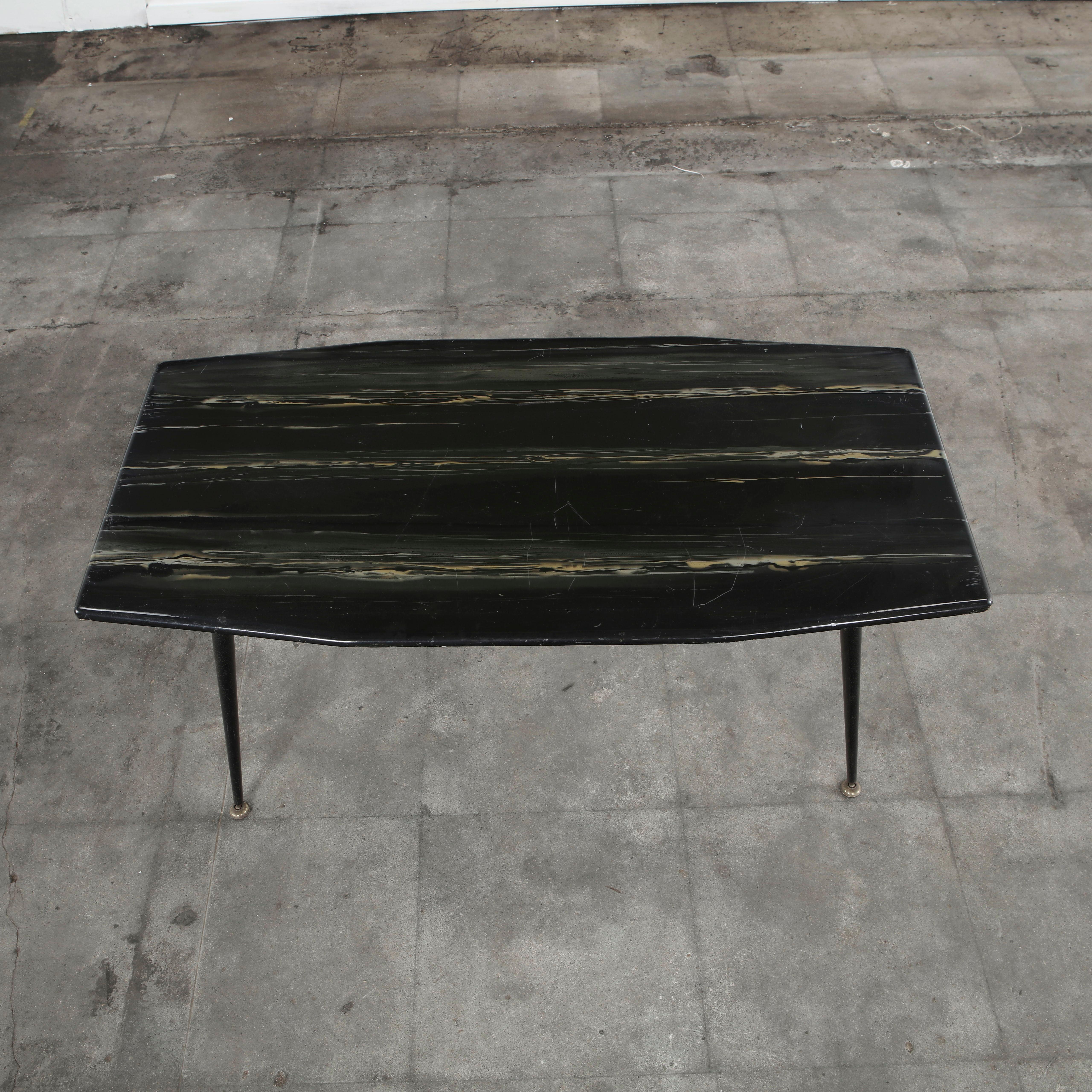 An elegant 1950s Italian coffee table distinguished by its sculptural silhouette and refined materials. The top features a black lacquered finish with subtle hand-painted striations in warm taupe tones, creating a soft linear pattern that adds depth