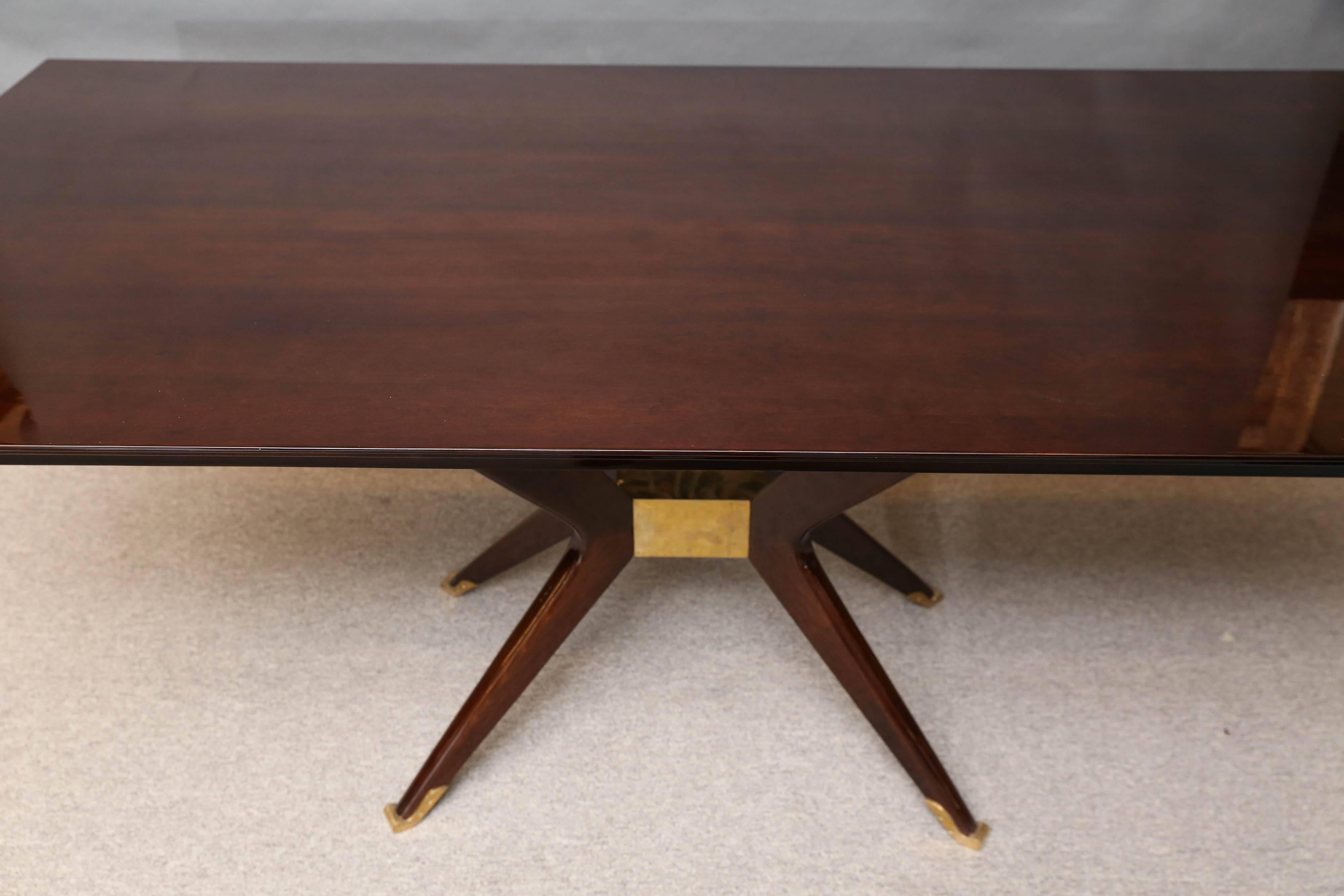 Highly polished palisander table. Resting on four boomerang shaped legs. The legs are connected to a brass 