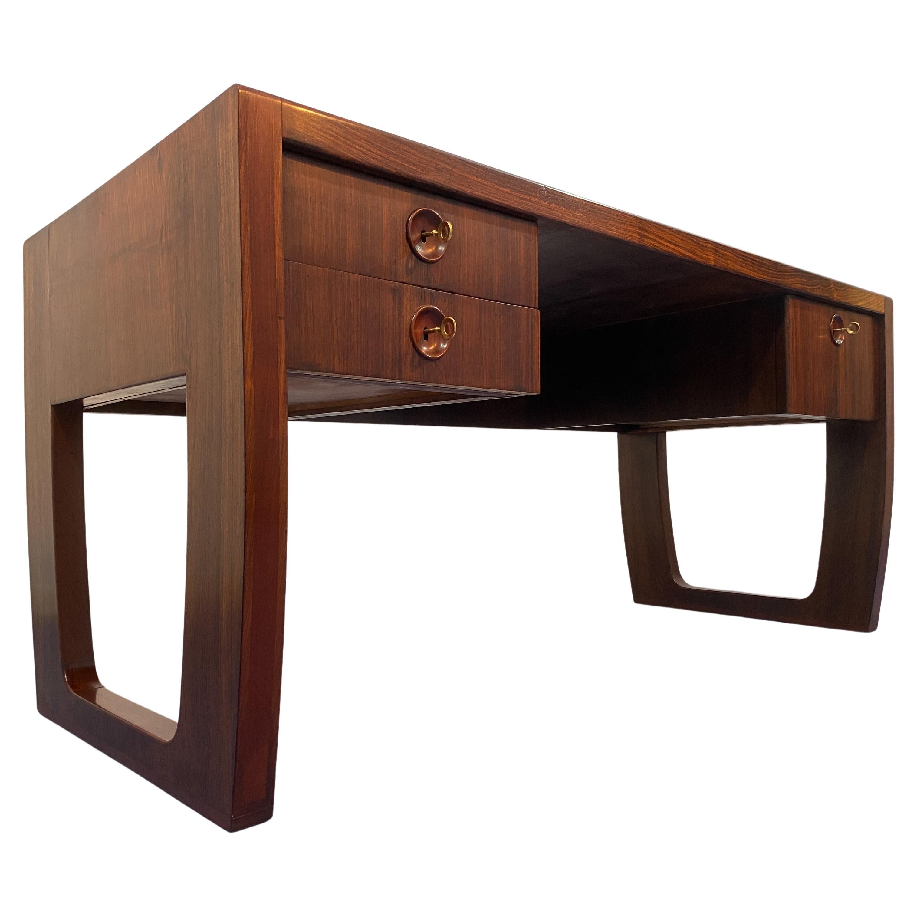 Elegante escritorio ejecutivo diseñado por Paolo Buffa en la década de 1950. El escritorio se caracteriza por la presencia de tres cajones laterales, dos similares en el lado izquierdo y uno más grande en el derecho. El diseño arqueado de los