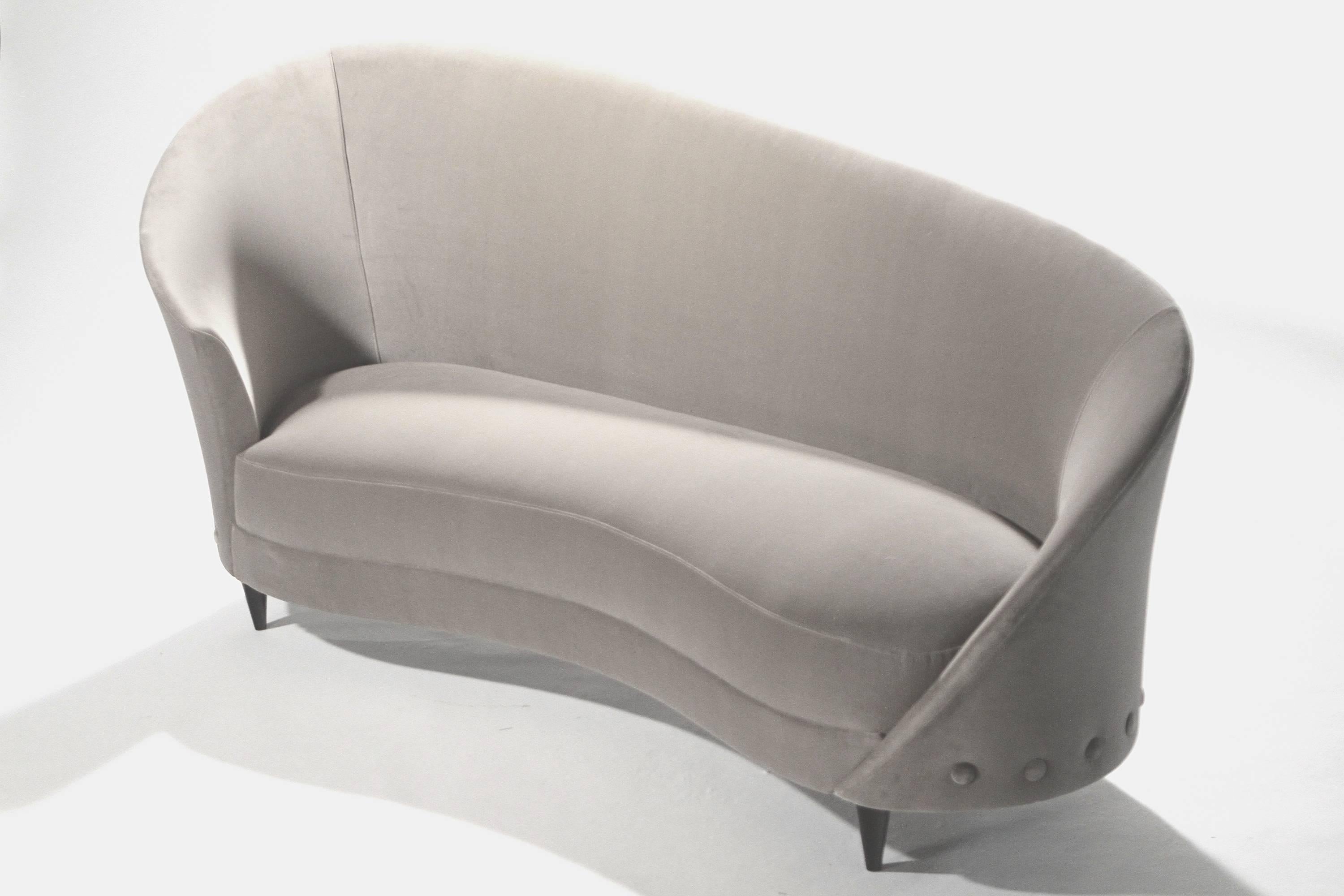 A rounded, sloped back gives this piece a jolt of midcentury glamour. Attributed to Italian designer Federico Munari, the sofa seems to belong in some glitzy, 1960s boudoir. However, the new trendy grey upholstery in soft velvet has made this piece