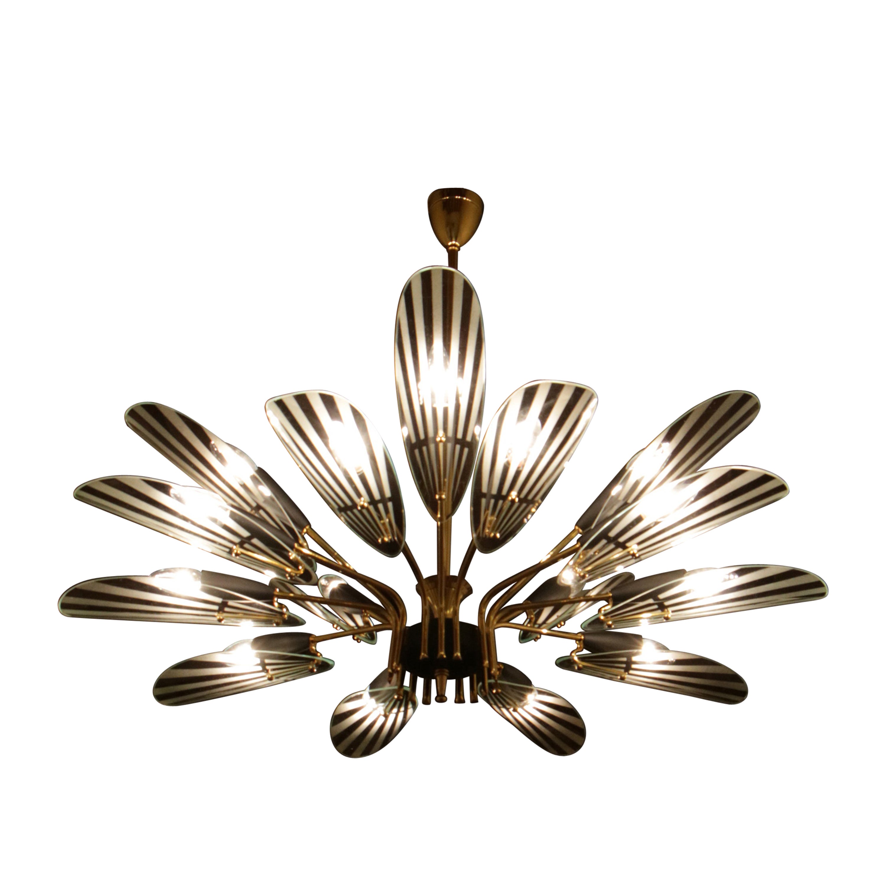 Lampadario italiano degli anni '50 del XX secolo, realizzato in ottone lucido e alluminio laccato nero, con vetri a foglia sabbiati. Dispone de 15 luci formato E14.

Esta lámpara de gran impacto escenográfico está destinada a convertirse en la