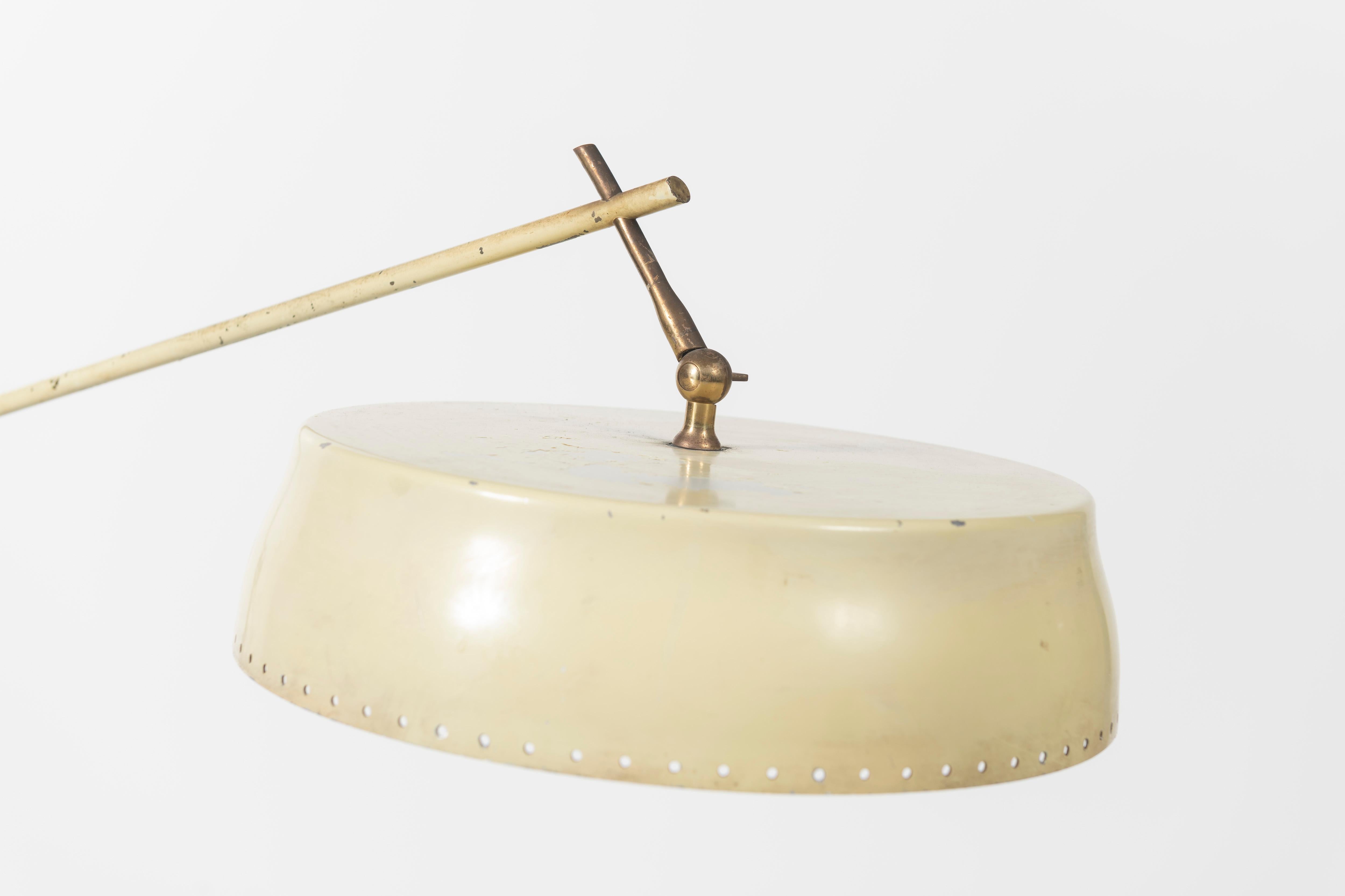 This floor light is designed by Angelo Lelli and made by his company, Arredoluce, in Italy. The cream colored aluminium shade is placed upon a brass articulated arm which is adjustable. The lamp rests on a base of Italian green marble. There is also