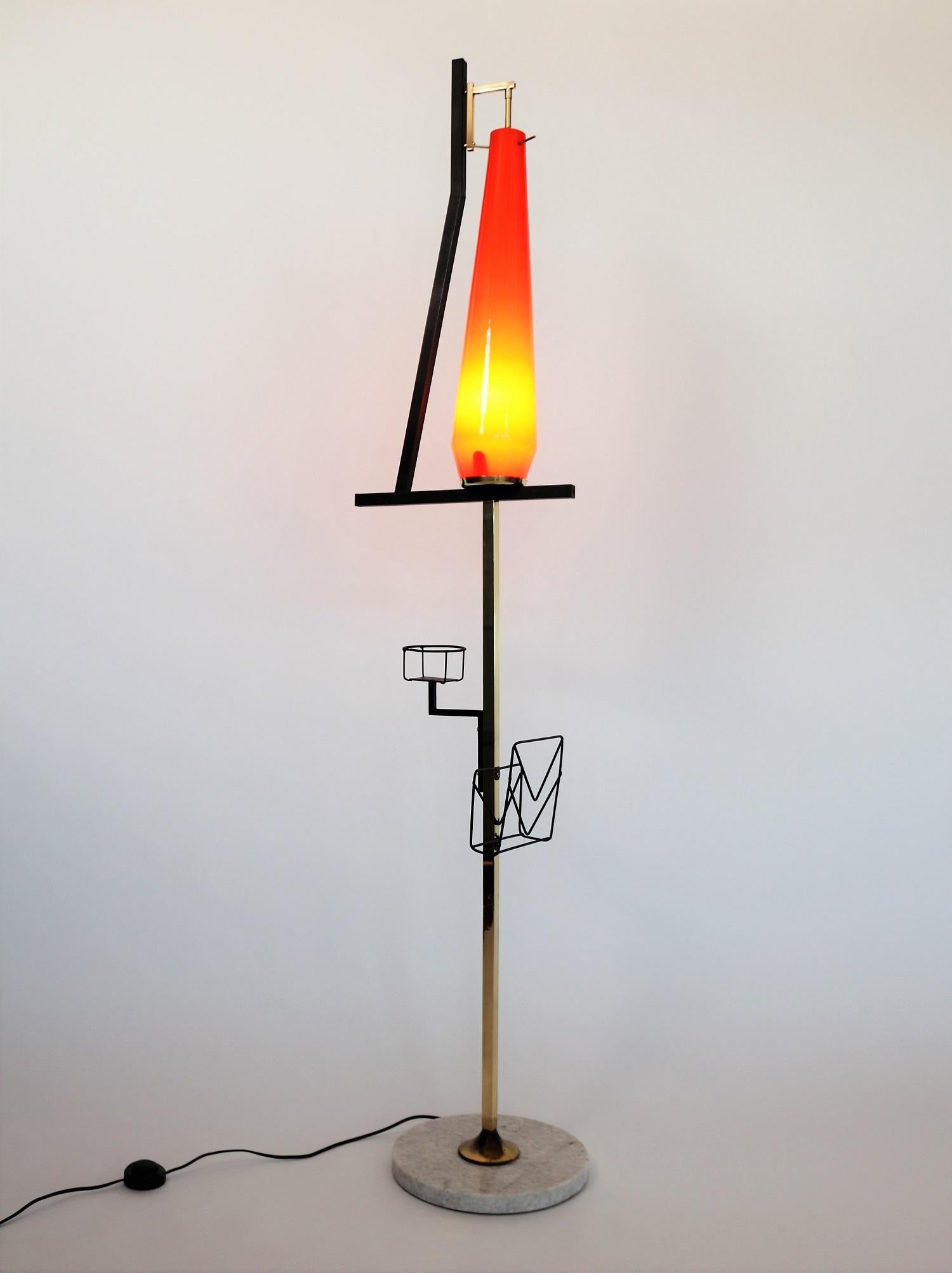 Crazy Italian floor lamp originally from the 1950s with shiny red glass and two metal holders for newspapers and a drink (?) or a small flowerpot. Stilnovo style.
The base is made of clear marble with some signs of wear and age.
The framework are