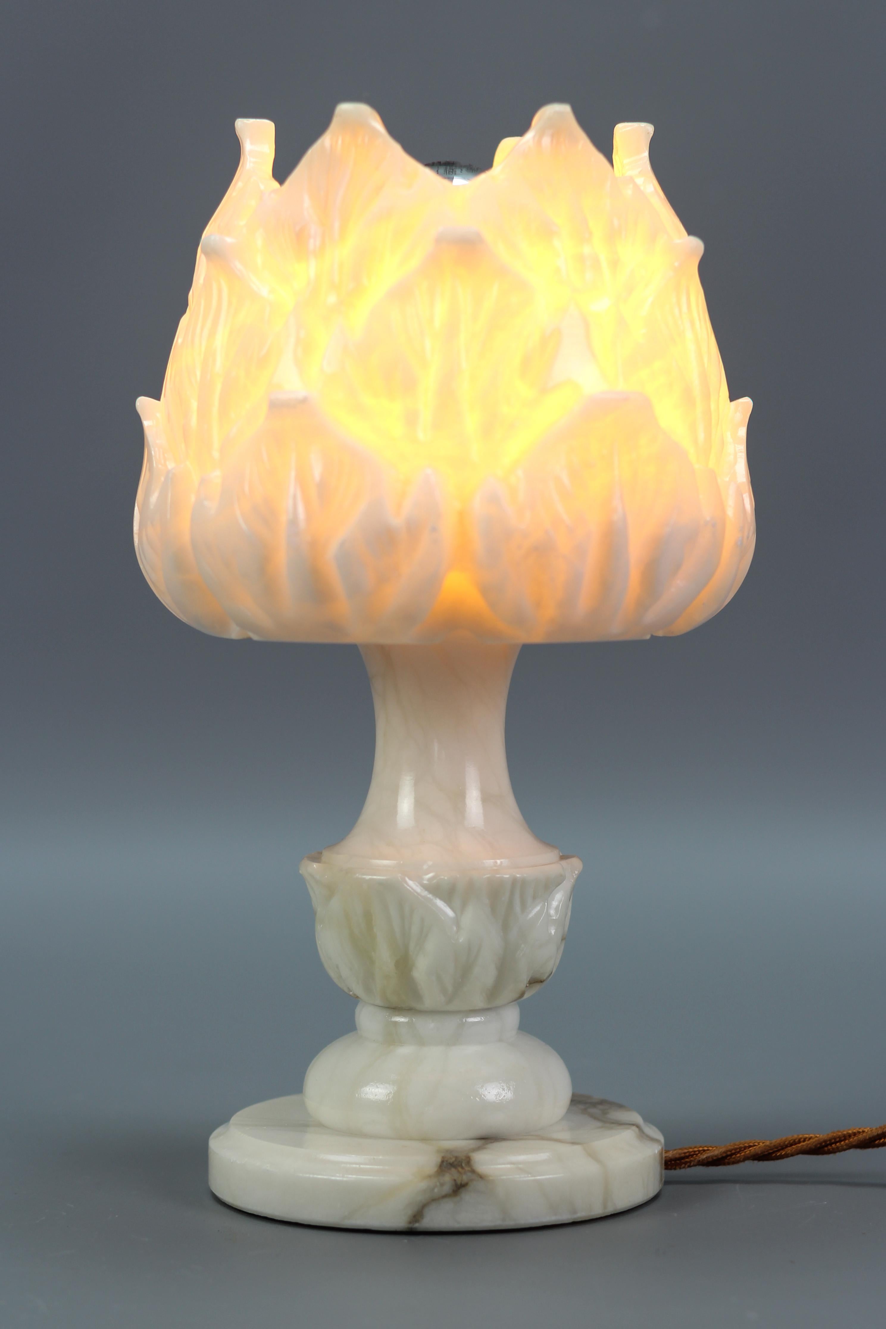 Italian mid-century flower-shaped white alabaster table lamp or mood lamp, from the circa 1950s.
Absolutely adorable white/ivory color alabaster table lamp or mood lamp in a shape of a flower with some dark brown and black veins. 
The light shining