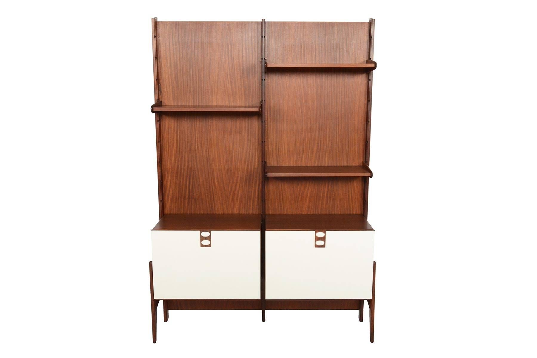 This handsome Mid-Century Modern Italian wall unit offers dynamic storage solutions in a small footprint! The two bay system is paneled in mahogany and includes three shelves and two cases that are completely modular. The unit stands on exterior