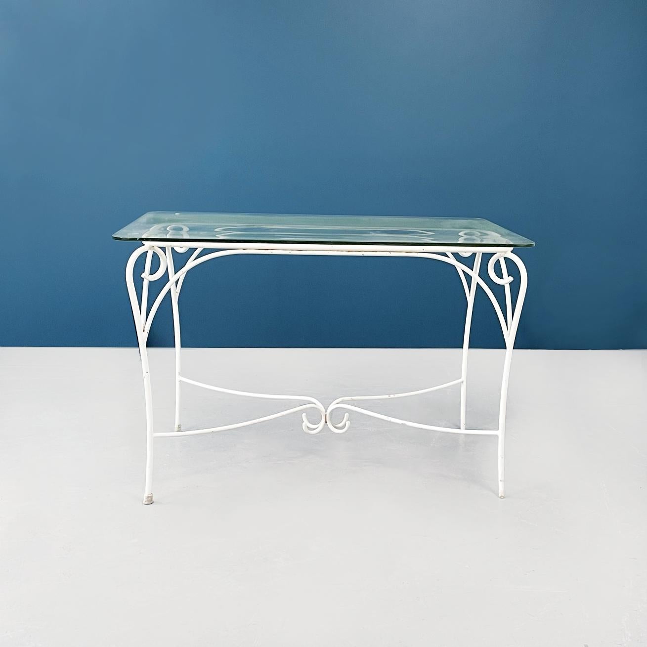 Italian mid-century garden table in white wrought iron and glass, 1960s.
Garden table in white painted wrought iron structure. The legs have decorative curls. The rectangular top in thick glass in aquamarine green has rounded corners and rests on
