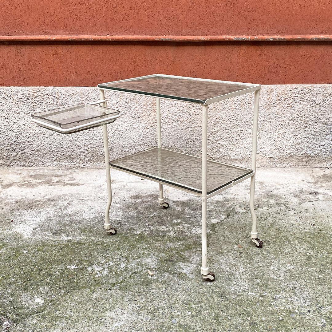 Italian mid century moved glass and white metal structure laboratory trolley on wheels, 1940s
Laboratory trolley on wheels with extractable shelf, and moved glass tops, frame entirely in white enamelled metal, with extractable compartment to