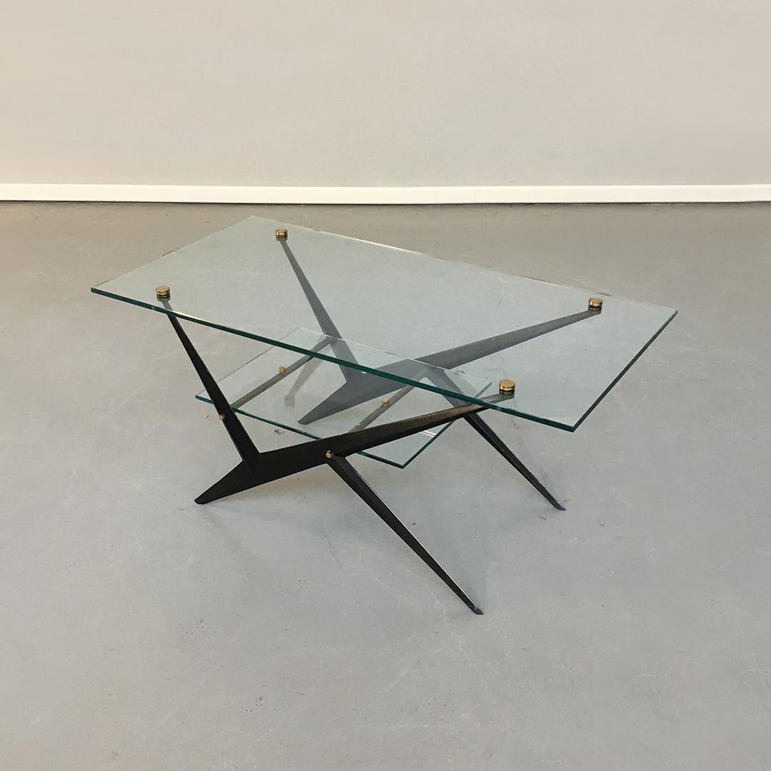 Italian midcentury glass, iron and brass coffee table by Angelo Ostuni, 1950s
Coffee table with rhomboidal section iron structure that holds two transparent rectangular crystals.
The buttons that fix the crystals are turned in brass and screwed to