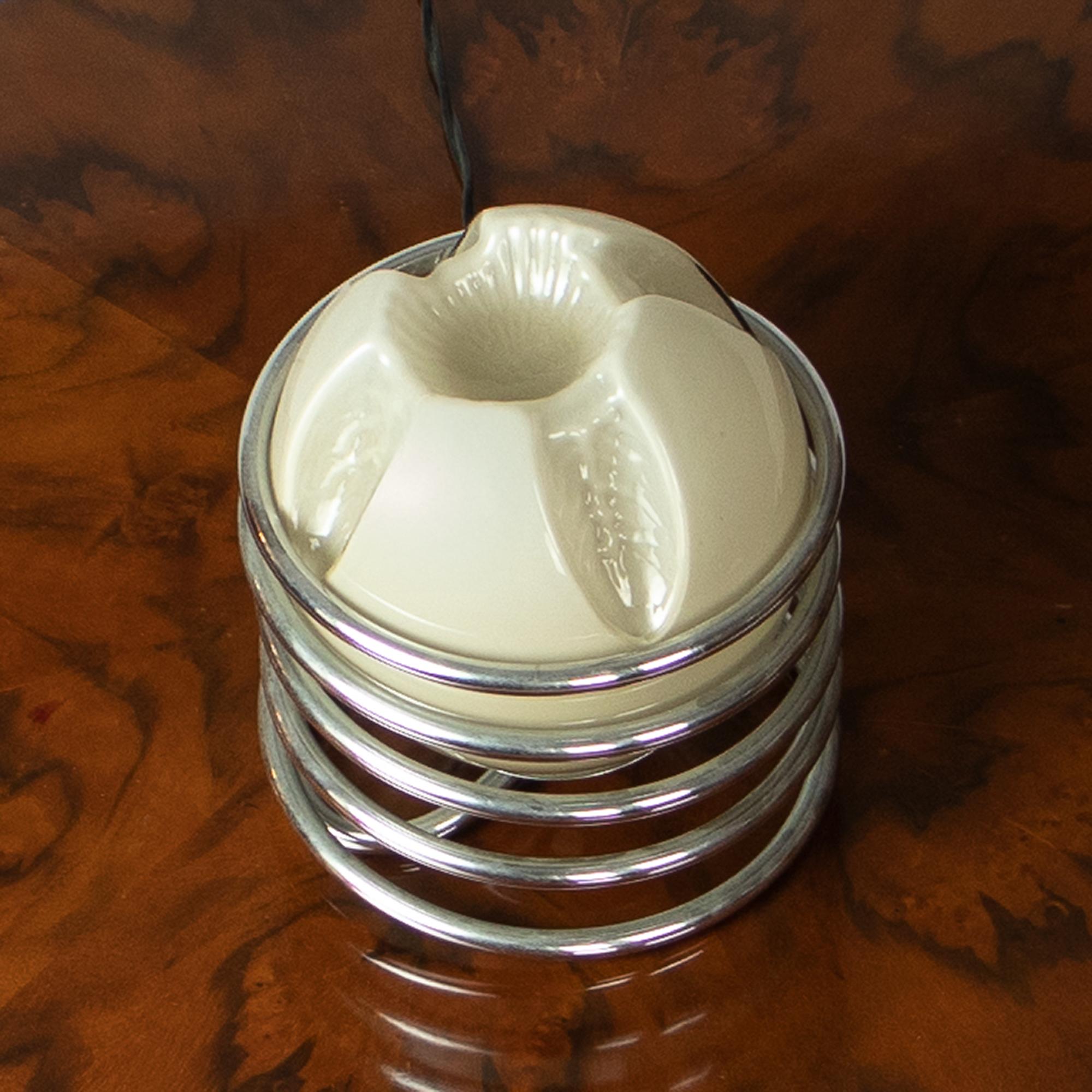 Cette lampe de table italienne du milieu du siècle présente une boule ronde en verre gris entourée d'une spirale en métal chromé, créant ainsi un effet visuel saisissant et moderne. 

Ses petites dimensions en font un complément idéal pour les