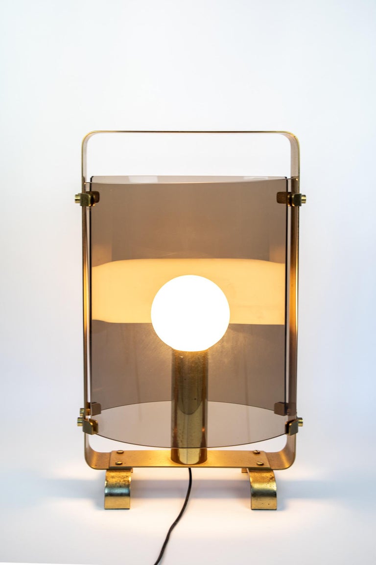 XL Table Lamp with Smoked Glass and Golden Brass, Italy, 1960s.

This one-of-a kind Italian table lamp has a golden brass frame with very special large brass nails. The frame is based on two curved pillars. On the front and on the back the table