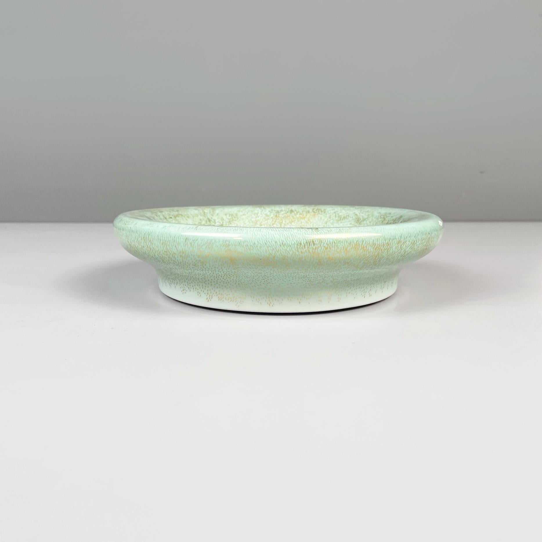 Italian midcentury Green light blue ceramic centerpiece by Mangani, 1960s.
Plate centerpiece with round base in ceramic: white in the center and blue-green sides with golden details. It can also used as pocket emptier bowl.
Produced by Mangani in