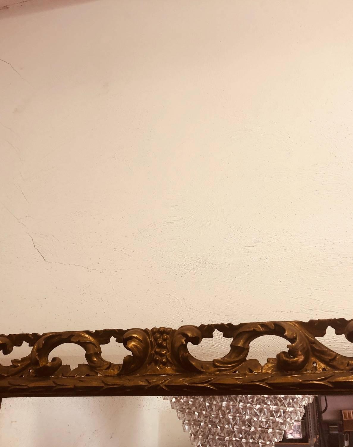 Klassischer, zeitloser italienischer Mid-Century-Spiegel, der die Traditionen der Moderne und des Neobarocks widerspiegelt, aus vergoldetem Holz mit einem handgeschnitzten, durchbrochenen Rahmen in Form einer Frucht.