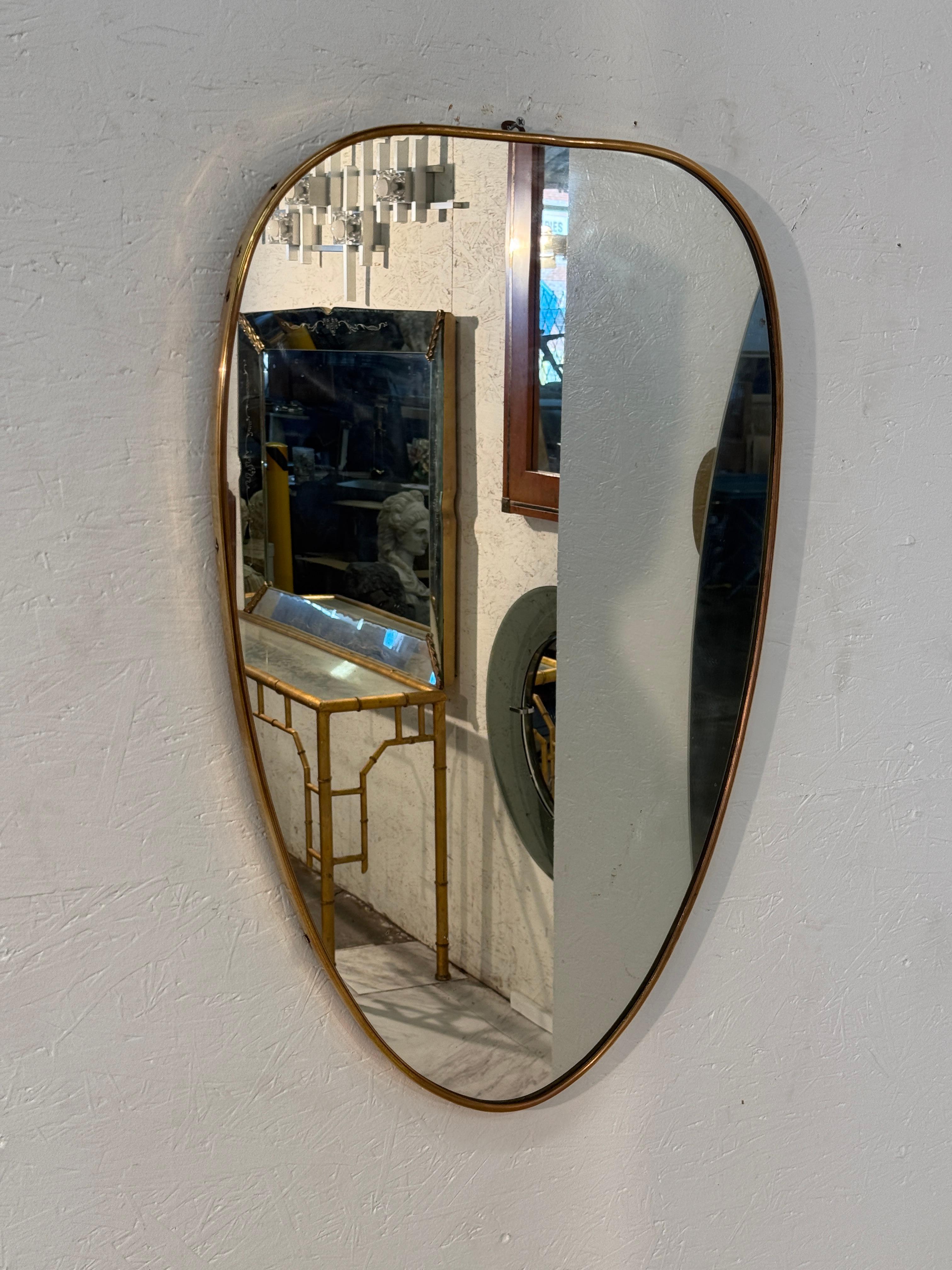 Un raffinato specchio da parete italiano di metà secolo con una forma organica a forma di cuore, incorniciata da un sottile bordo in ottone. La sua silhouette morbidamente curvata combina eleganza e semplicità, mentre i bordi in ottone caldo