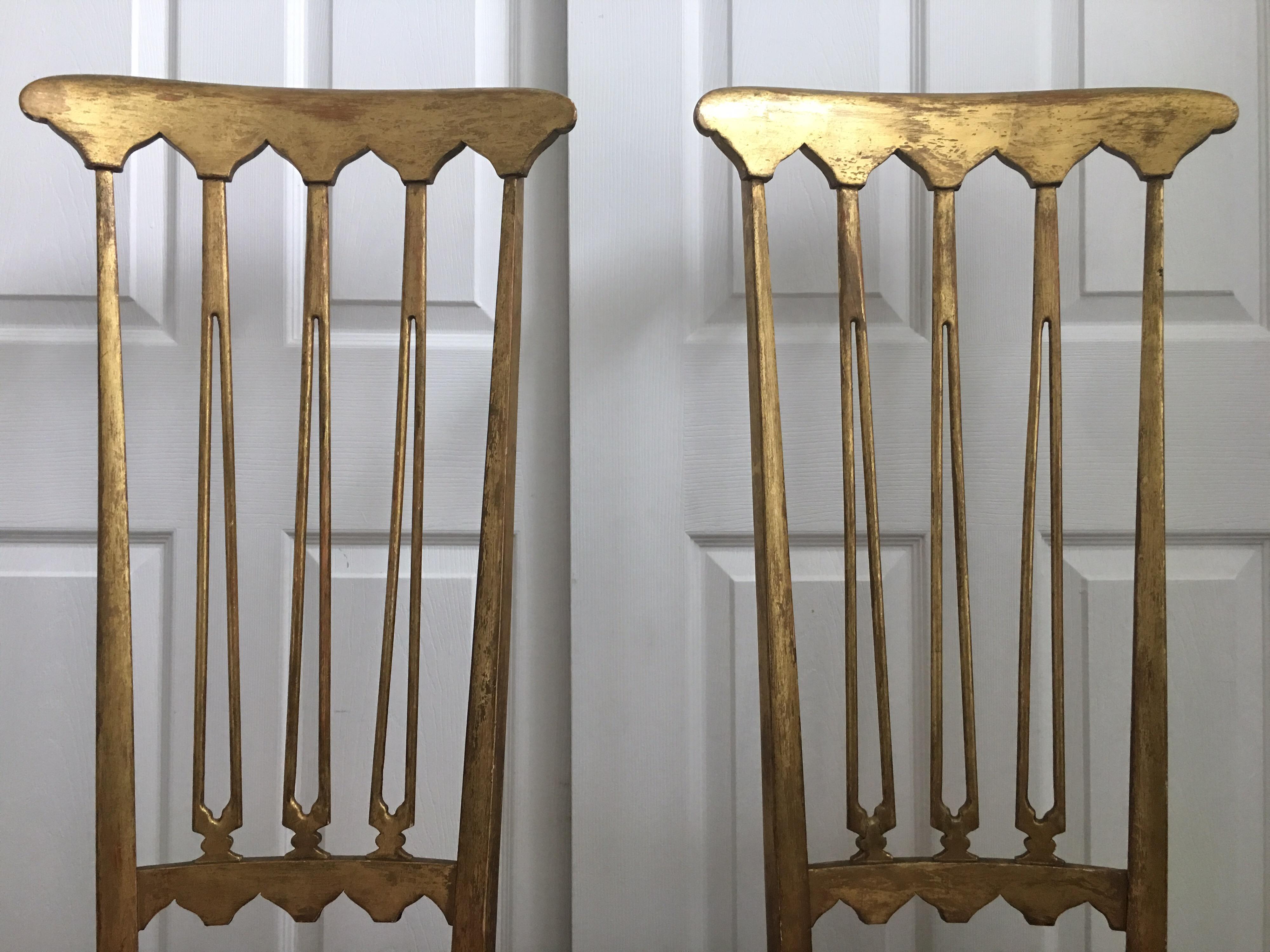 Pair of Mid-Century Modern Hollywood Regency style gilded wood Chiavari side chairs. These tall high back Italian chairs feature hand carved wood detailing and striped upholstered seats. Dramatic accent seating for a dining or living room.
 