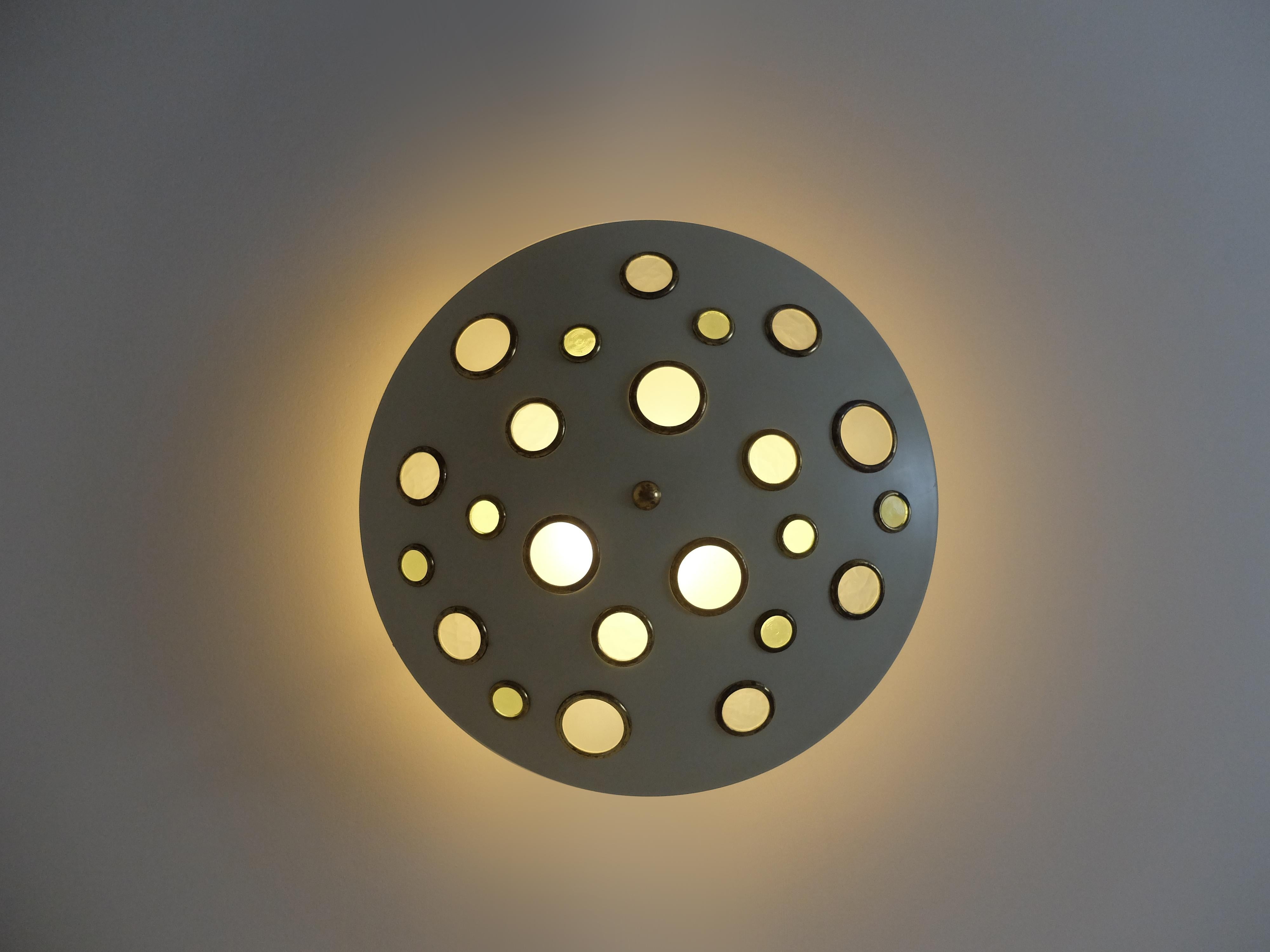 Monumental Italian Mid-Century Modern flush mount plafon from Stilnovo, consisting in a large off-white laquered turned metal main structure holding 25 round brass and texured glass elements. 

The light sources, radially positioned between the two