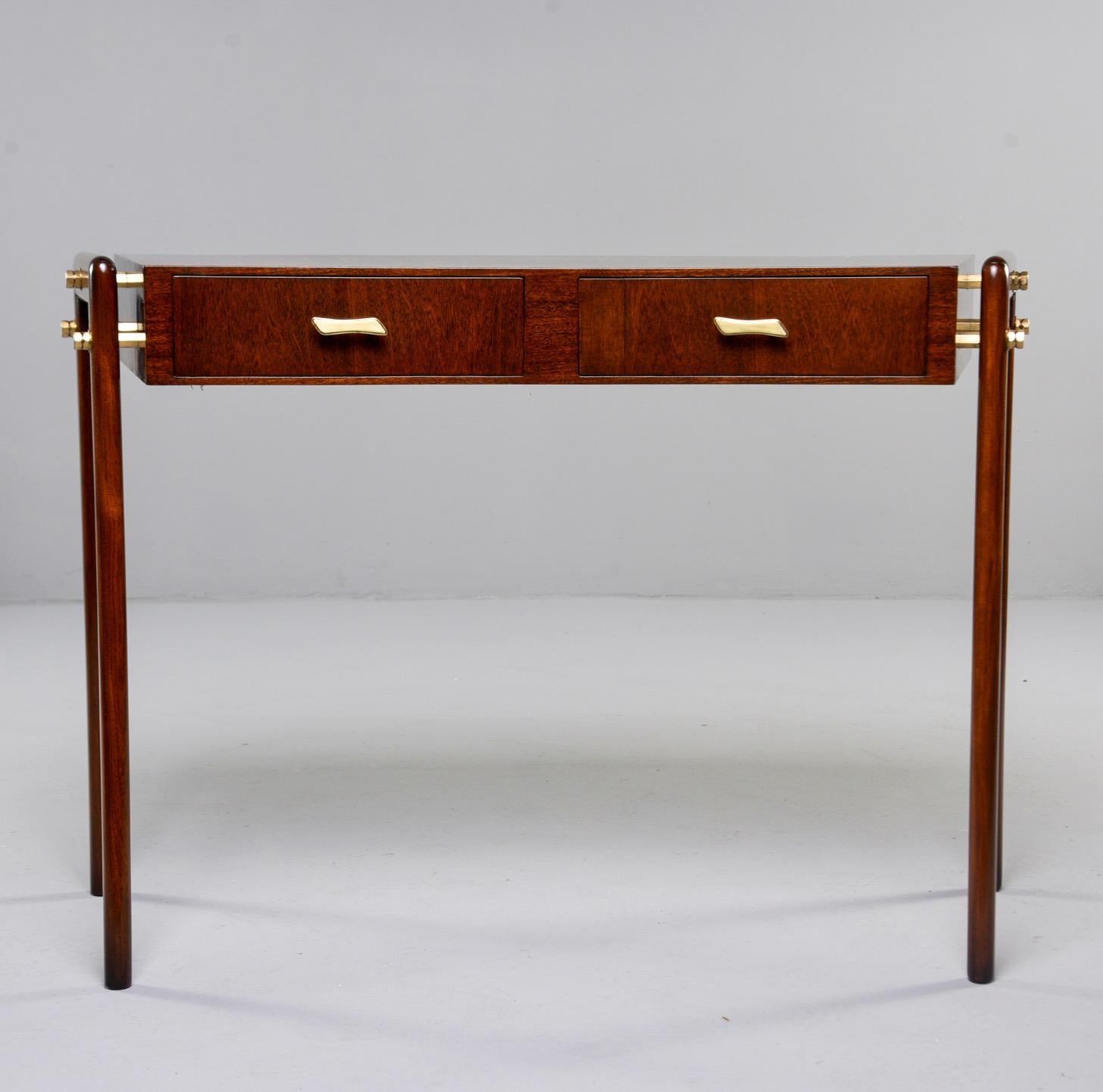Italian writing desk with great midcentury style, circa 1960s. Beech desk with mahogany veneer and brass hardware features a subtly curved front with two functional drawers and sleek legs attached at the sides. Unknown maker. Found in Italy.
 