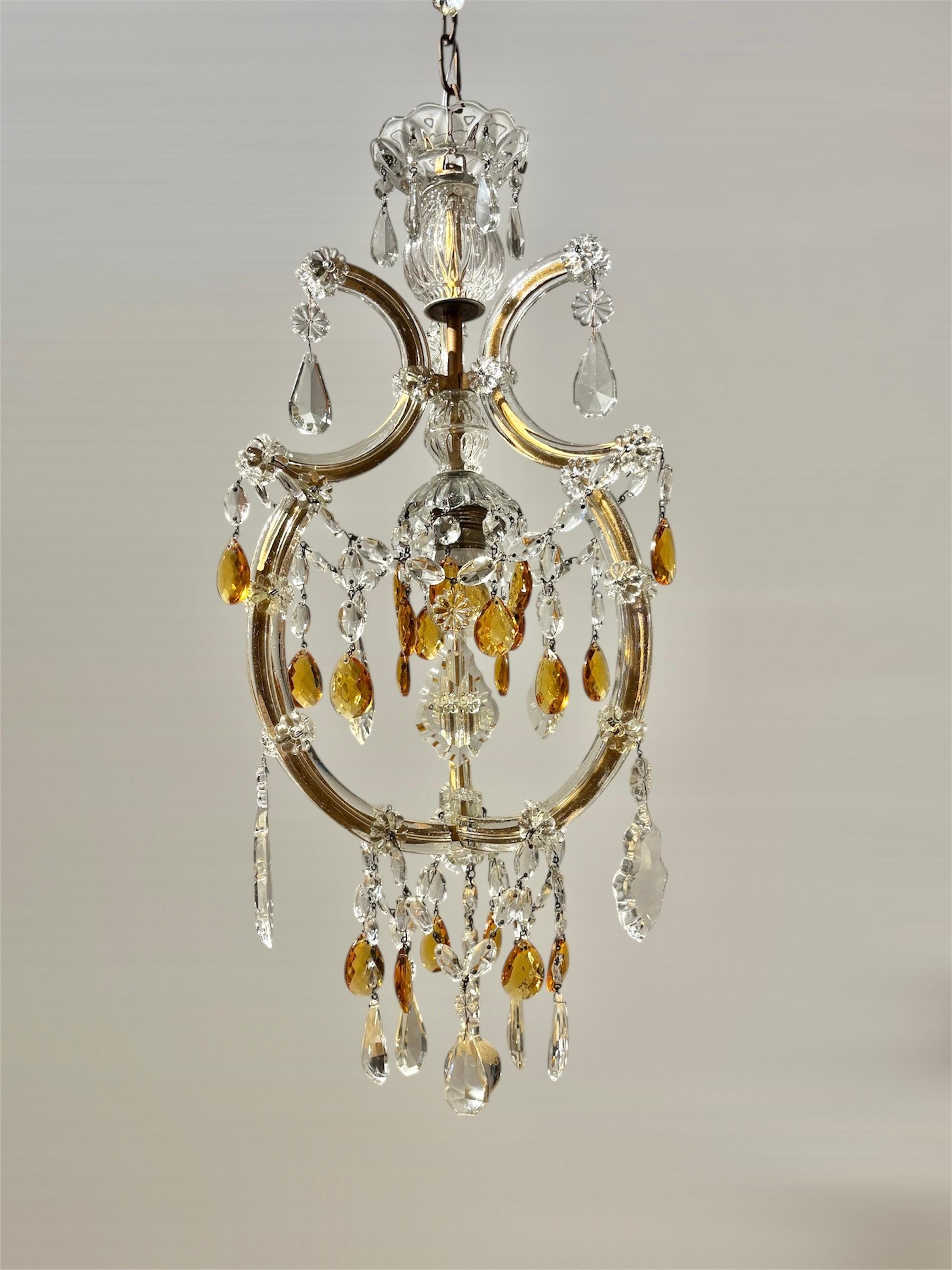 Esta refinada araña italiana Maria Teresa de los años 50 presenta una única luz central rodeada por un elegante marco de metal dorado ricamente aderezado con auténticos elementos de cristal de Bohemia. El diseño muestra la clásica construcción María