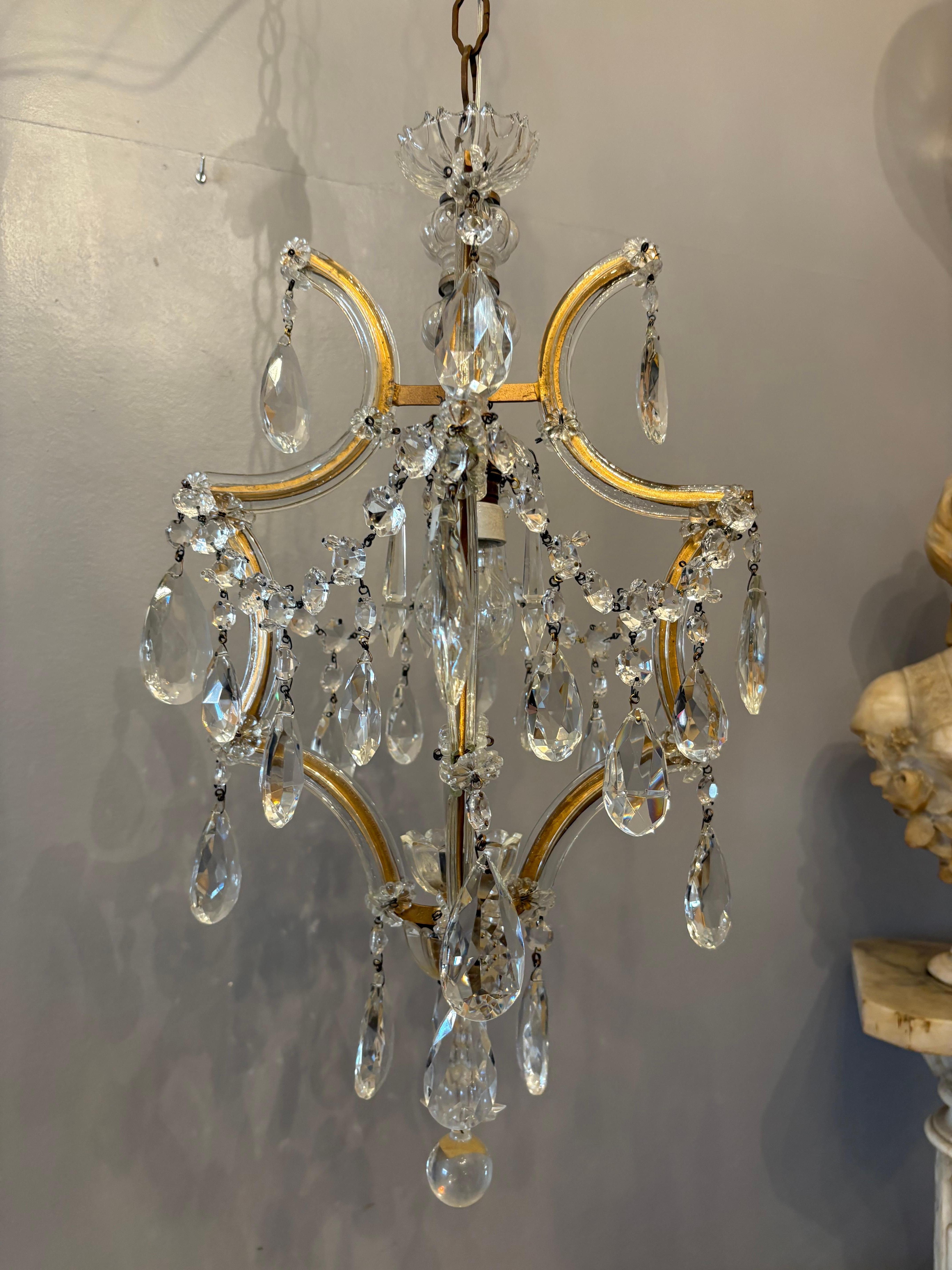 Elegant single-light Maria Theresa chandelier handcrafted in Italy during the 1950s. This refined piece features beautifully curved gilt metal arms adorned with hand-cut Bohemian crystal drops and glass rosettes. The chandelier sparkles with clarity