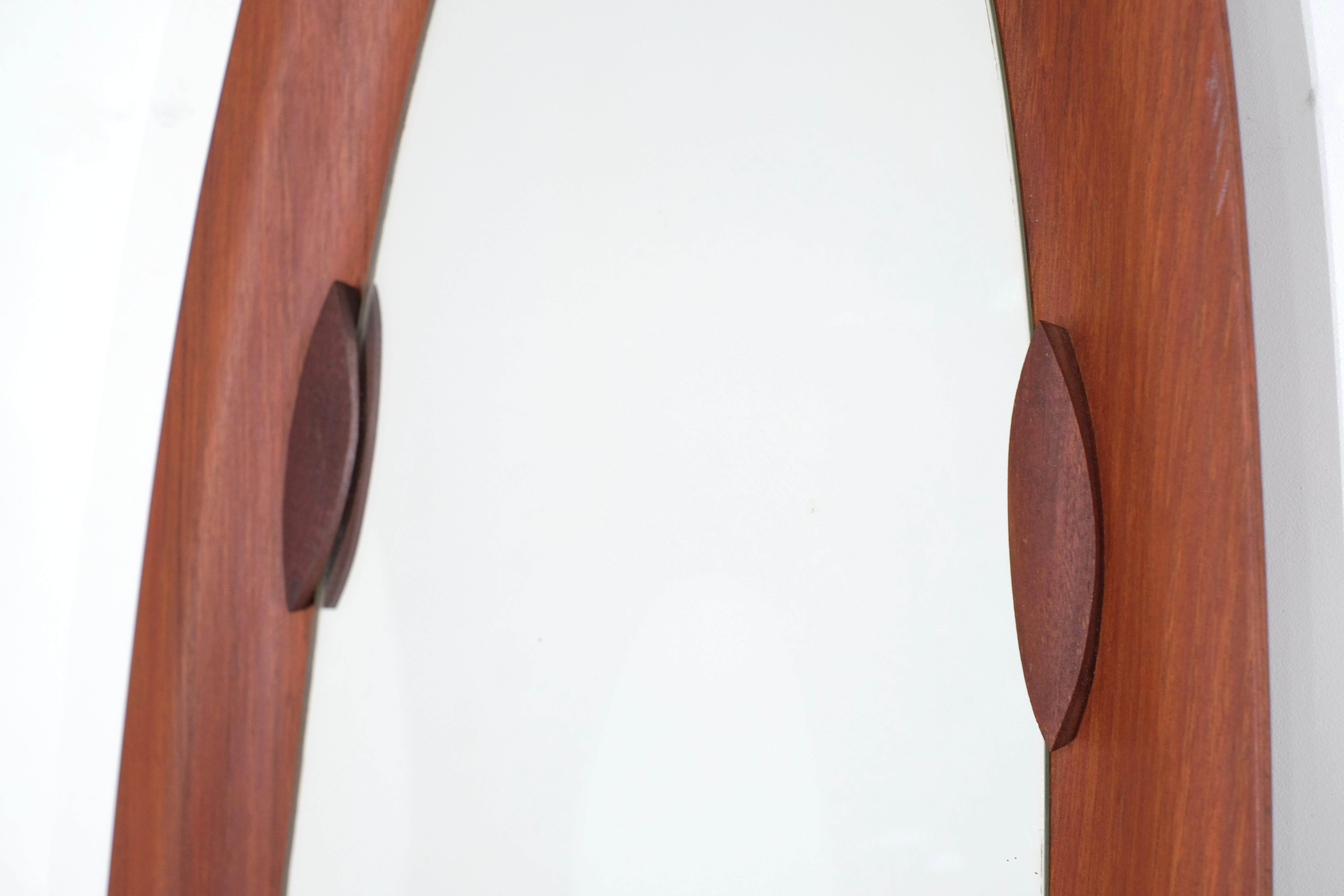 Magnifico specchio italiano in legno disegnato negli anni '60.

La sua forma ovale allungata gli conferisce un design magnifico.
Lo specchio è sostenuto da quattro elementi di fissaggio in legno che completano perfettamente lo specchio e ne