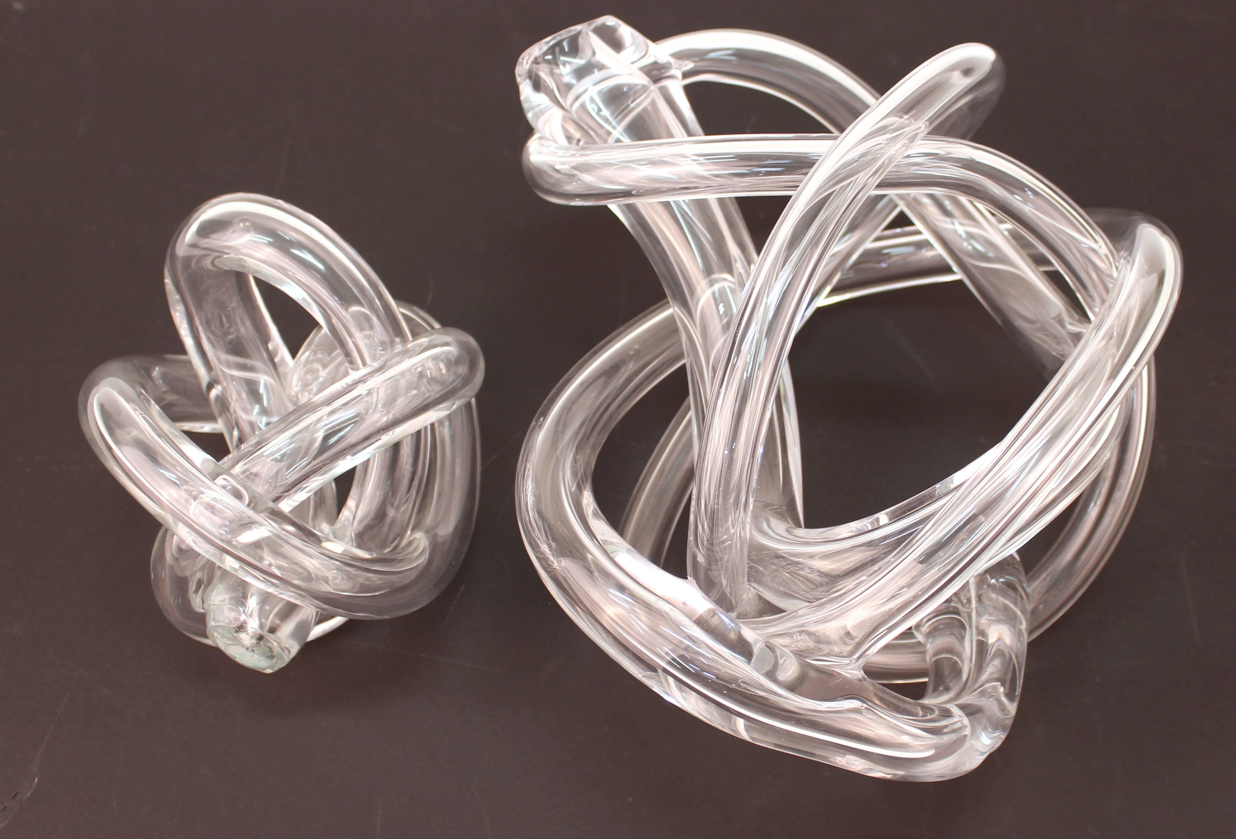 A set of two Italian Mid-Century Modern handblown art glass sculptures forming abstract knotted shapes, one smaller and one larger, in clear glass. The set is in excellent condition.