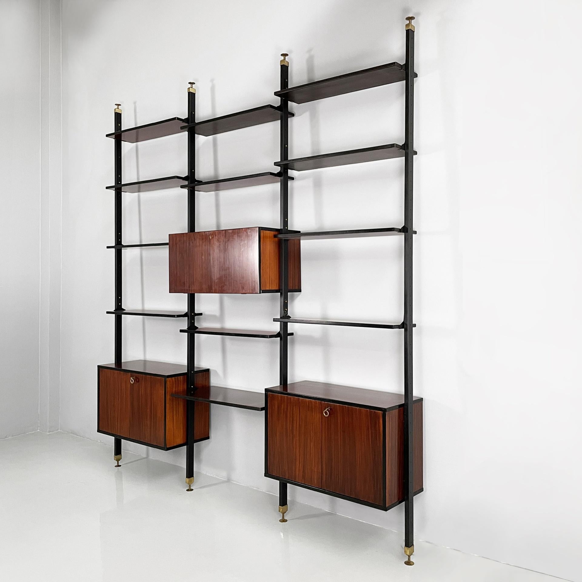 Italian mid-century modern bookcase in wood, brass and black metal, 1960s
Modular floor-to-ceiling bookcase in black painted metal and dark wood with black profiles. It is composed of eleven rectangular shelves, a larger shelf, which can be used as