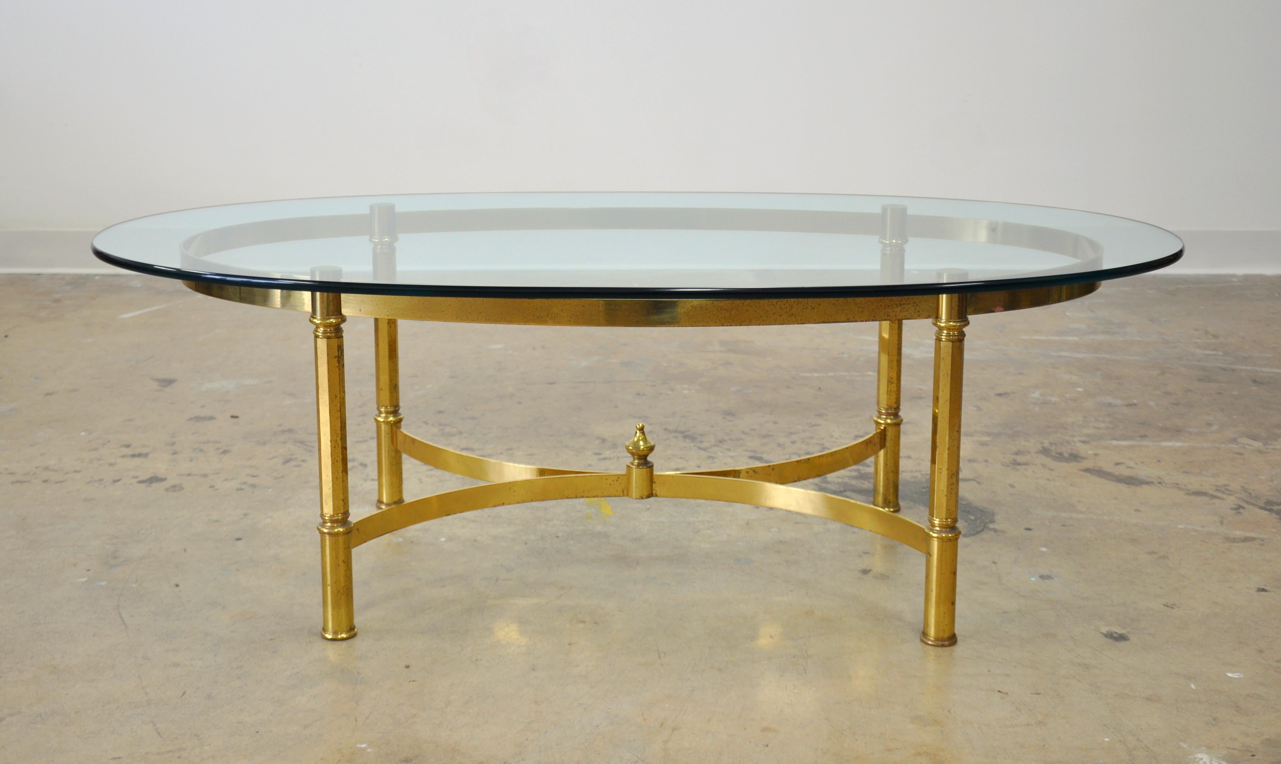 Vintage Mid-Century Modern brass cocktail table, with glass top. The Hollywood Regency table features a removable clear glass top, curved stretcher supports and decorative brass accents. Stamped 
