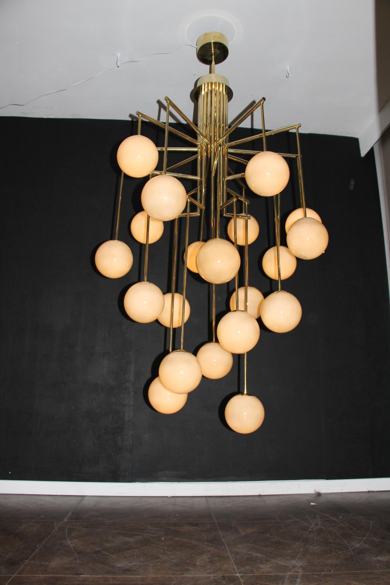 This chandelier features eighteen lights. It is very unusual shape.Its frame is in brass and has got geometrical shape.
Each vertical arm is finished by a hand blown Murano glass globe. Color of these glass globe is between light grey and light