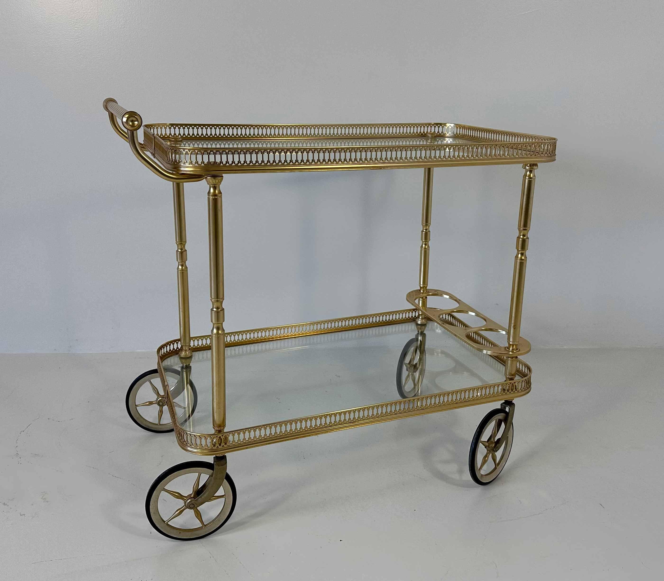 This unique tray table was produced in Italy in the 1970s. 
It is composed by a gilt brass structure and a gilt brass bottle holder, with two glass shelves and wheels. 
Labeled 'Patent Mb, Made in Italy'.
In perfect vintage conditions.
   