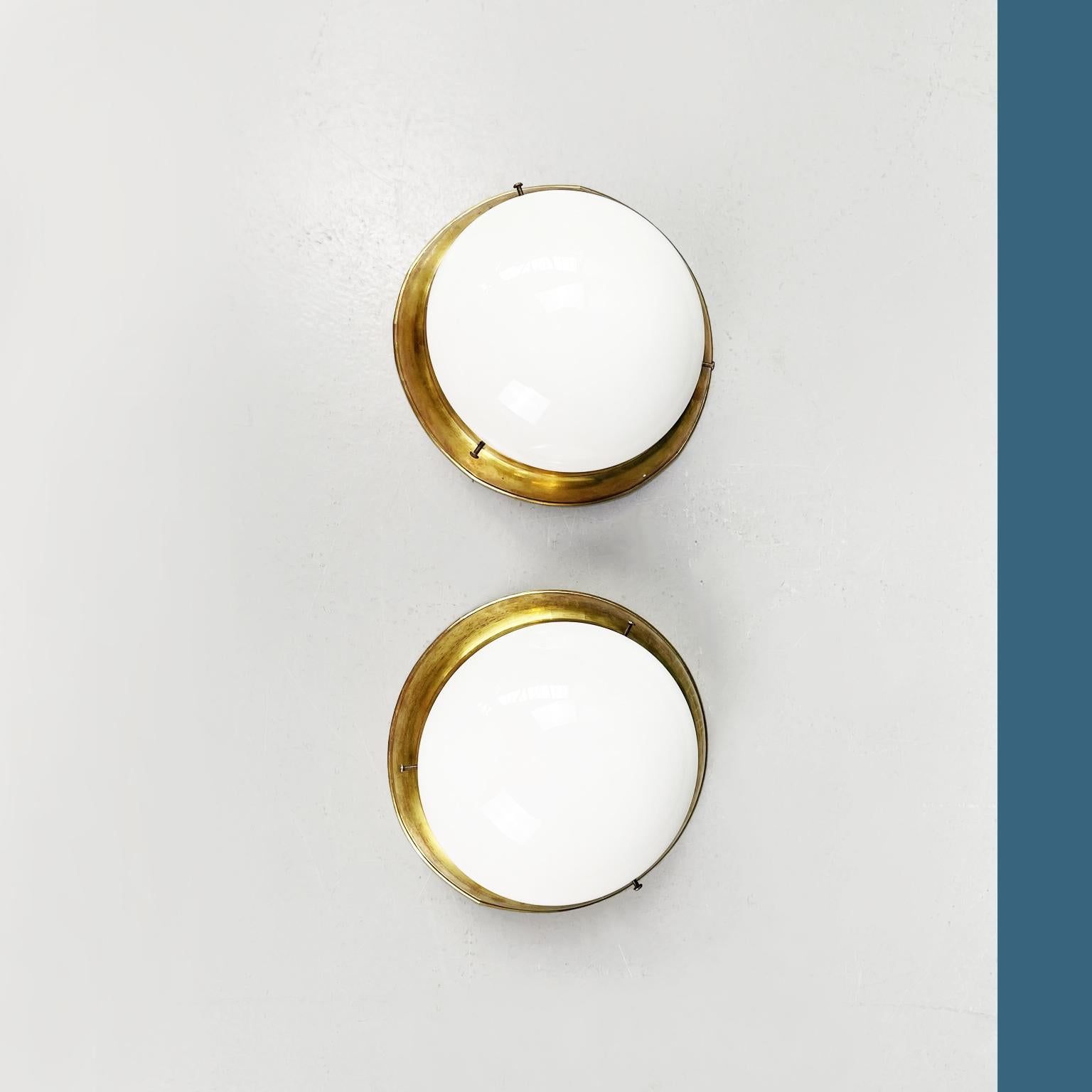 Italian mid-century modern Brass and opaline glass round wall lights, 1960s
Pair of round wall lights in opaline glass and brass. The lampshade is composed of a semi-sphere in opal glass. The structure is in brass with visible pegs.

1960s.

Very