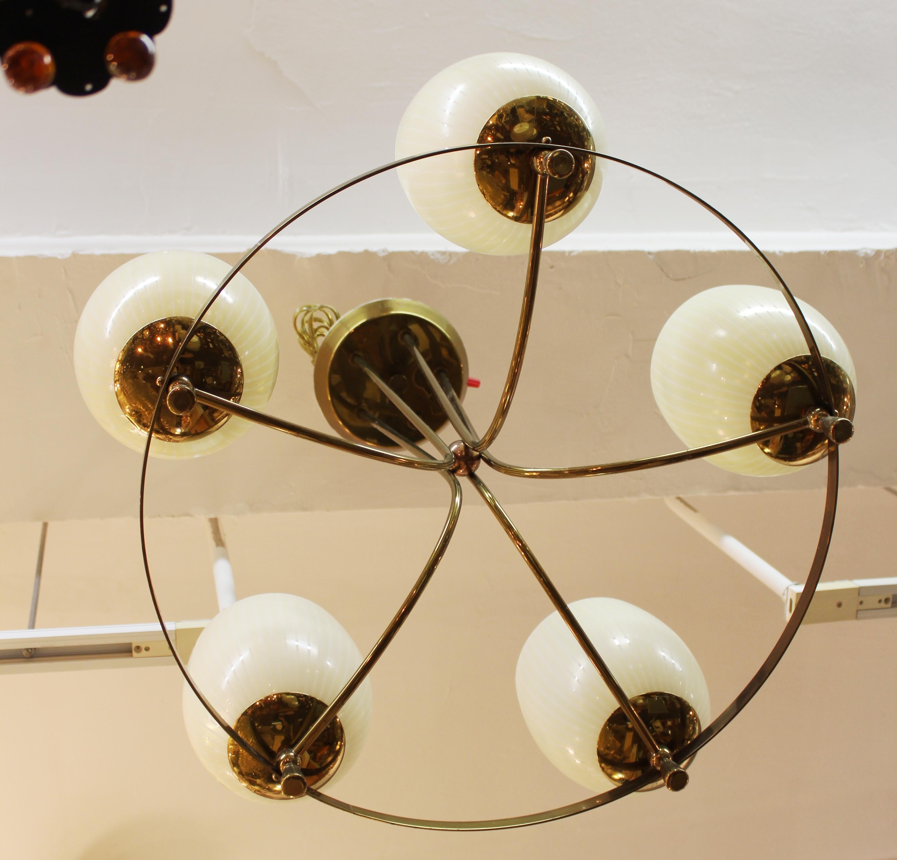 Mid-Century Modern one-tiered chandelier with circular brass structure and five arms holding open glass globes. The piece was made in Italy during the mid-20th century and has recently been rewired to fit current standards. In good vintage condition