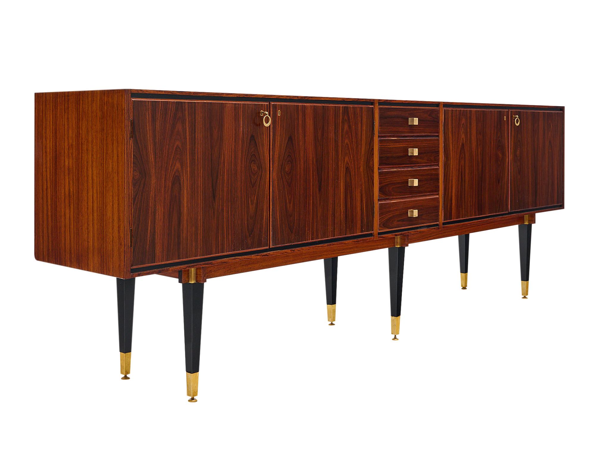 Buffet/Credenza, Italian Mid-Century Modern, made of figured Brazilian rosewood. This finely crafted enfilade features two sets of double doors with original working locks and keys, opening to adjustable shelves. The cabinets are separated by four