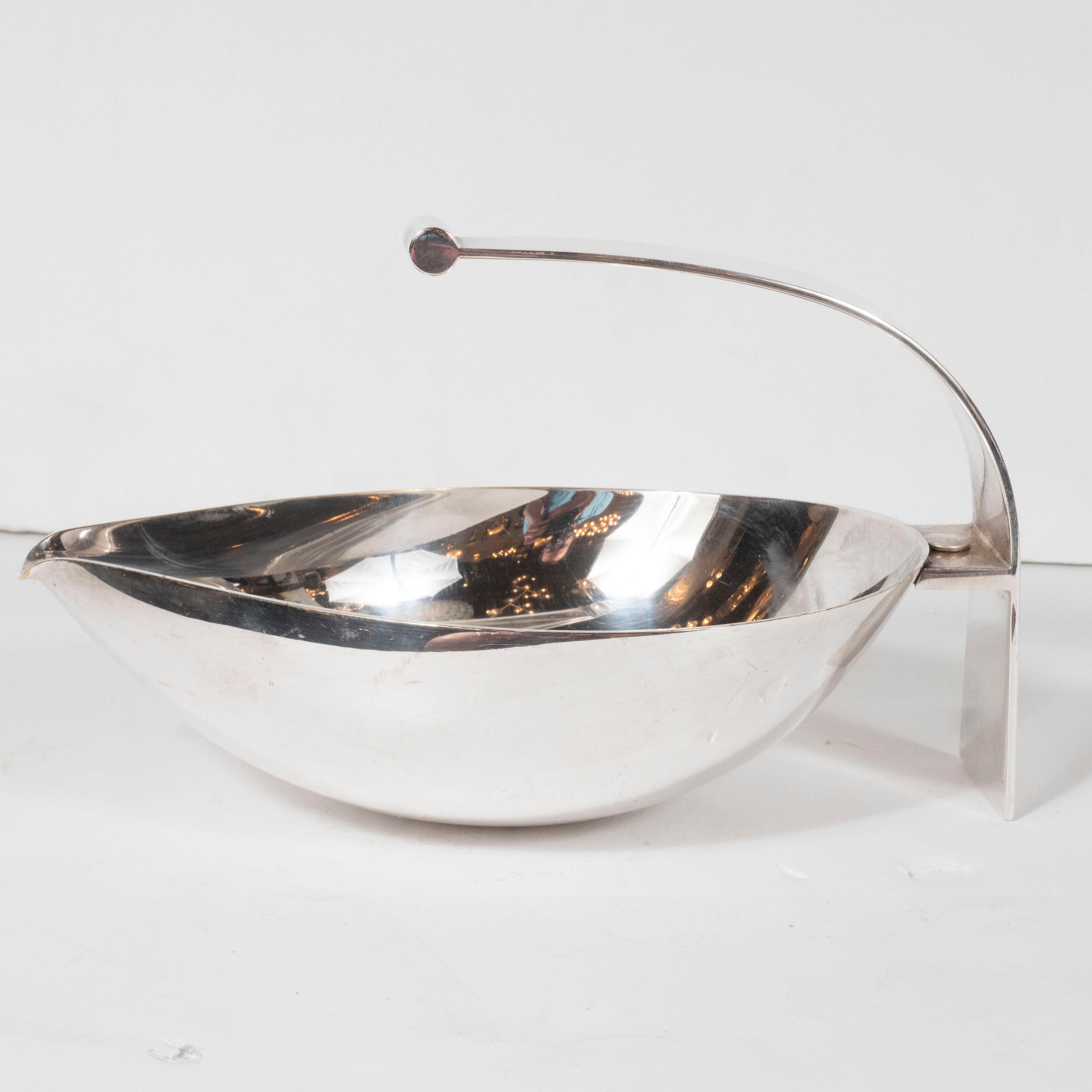 This elegant and atomic Mid-Century Modern silver plated decorative dish was realize by the celebrated Italian Mid-Century Modern firm Mesa circa 1960. It features an ovoid body with a curved handle that cantilevers over the body. With its