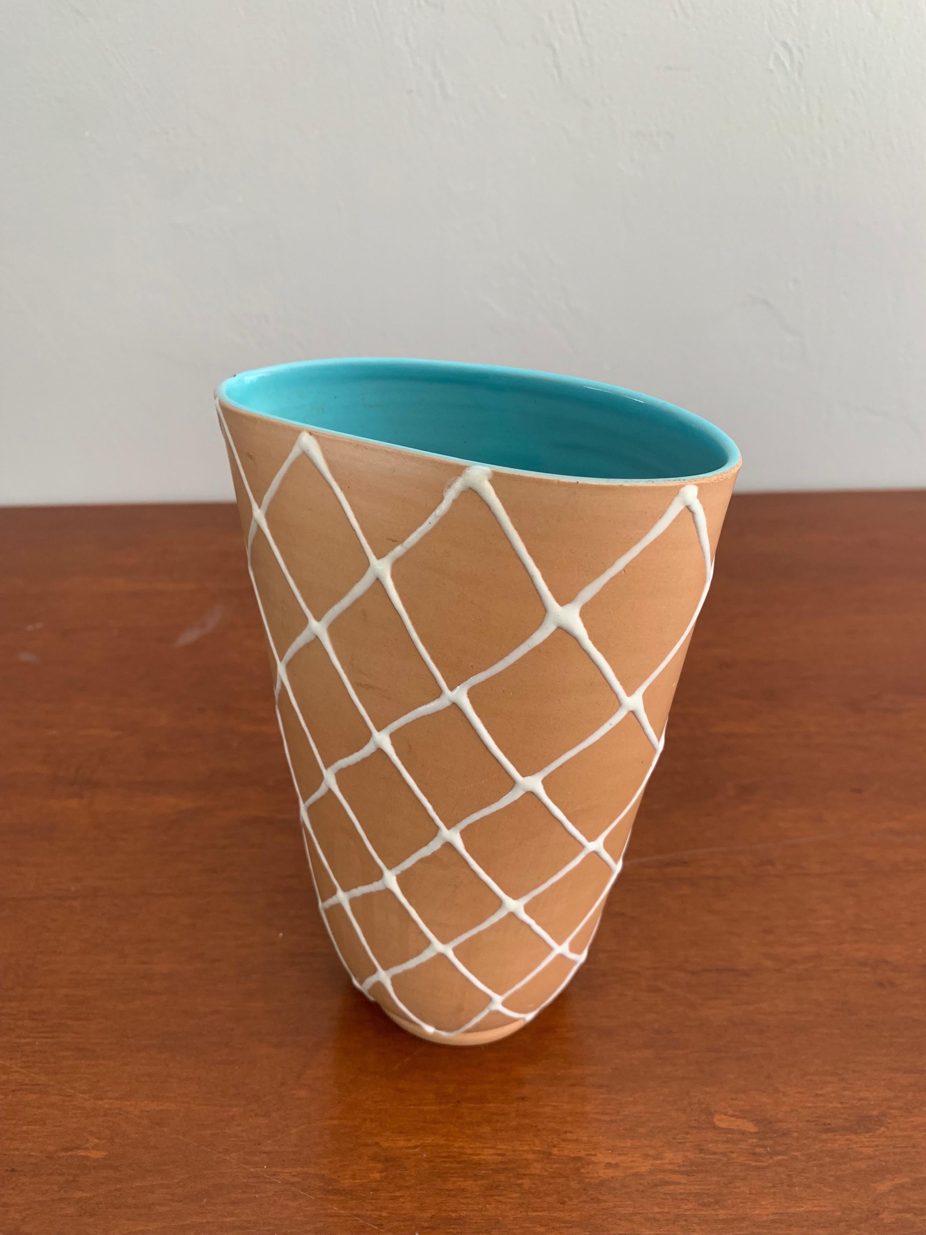 Lovely Italian Mid-Century Modern vase by Alvino Bagni.

A tan exterior with a crisp white cross pattern hiding a beautiful blue glazed interior. 

Vase is 7.5” tall 5” wide and 3.5” deep.