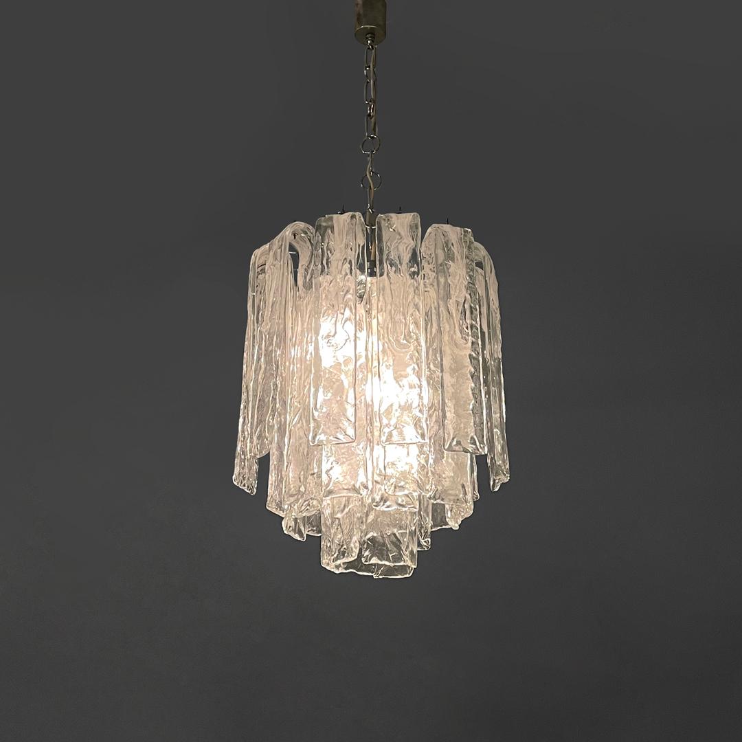 Italian mid-century modern chandelier transparent and white Murano glass, 1960s
Round base chandelier in transparent Murano glass with white shades. The cylindrical structure is made up of three rows of textured glass strips that bend to form a 