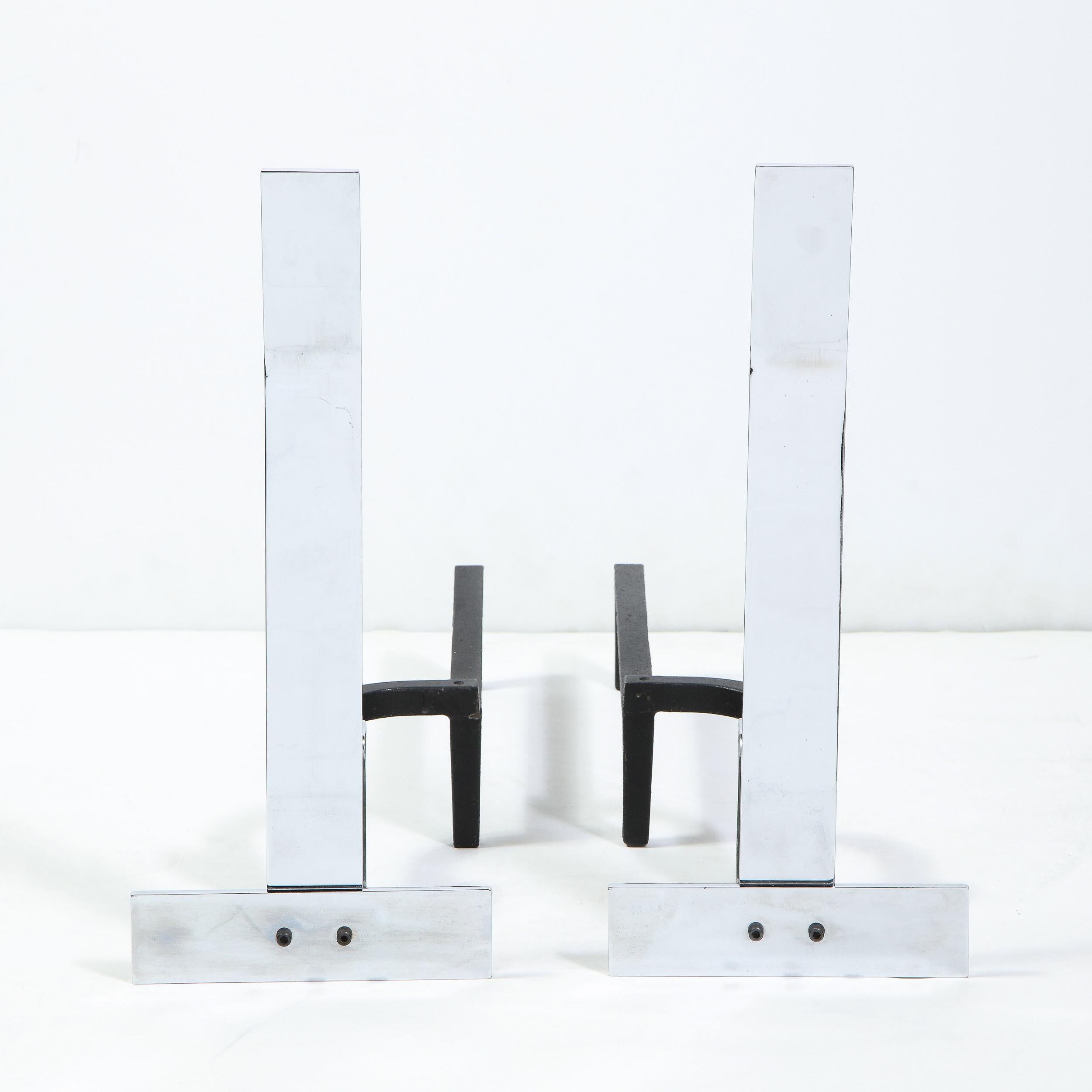 This sophisticated pair of modernist andirons were realized by the esteemed designer Alessandro Albrizzi, in Italy, circa 1970. They feature inverted T-forms consisting of a horizontal band bisected at its center by a vertical band that ascends at