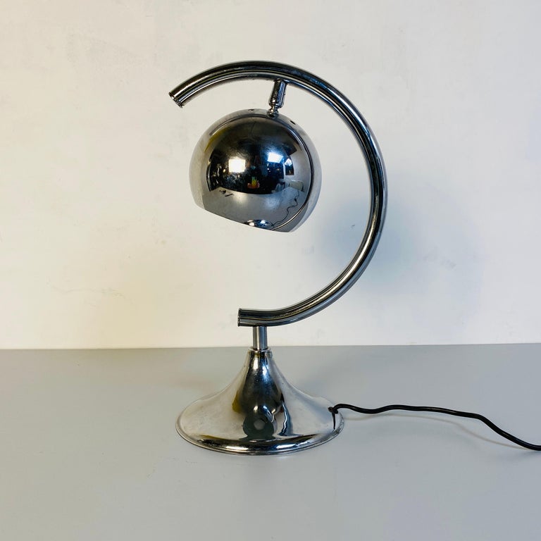 Italian Mid-Century Modern chrome table lamp with semi-circular structure, 1970s
Chrome table lamp with semi-circular structure containing a sphere lamp holder.

Very good condition

Measures 26 x 18 x 39 H cm.